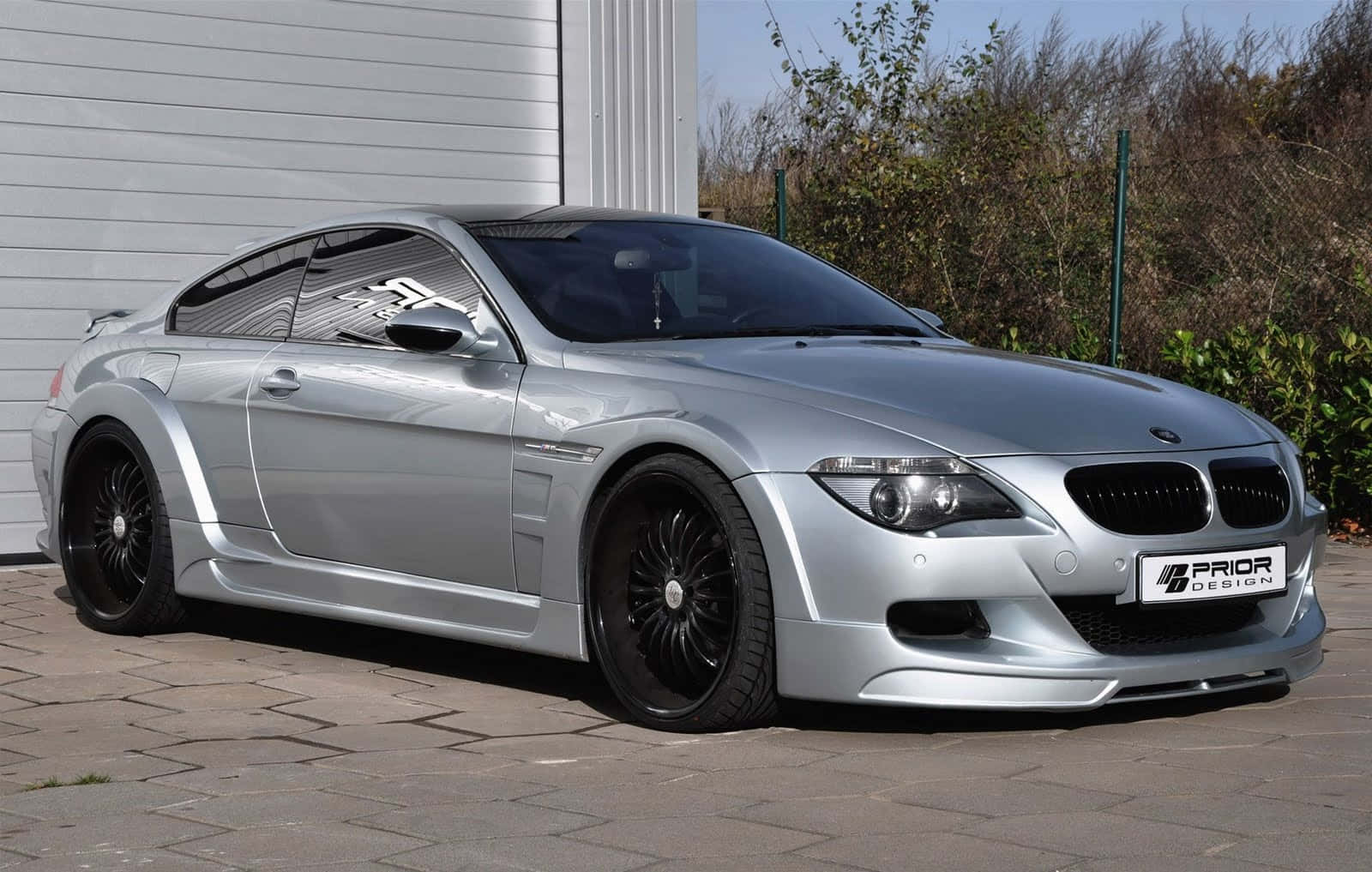 Bmw M6 桌布 壁紙 — 一架型格銀色BMW M6雙門跑車配黑色輪圈，停泊在白色車庫和綠化旁的鋪砌車道上。