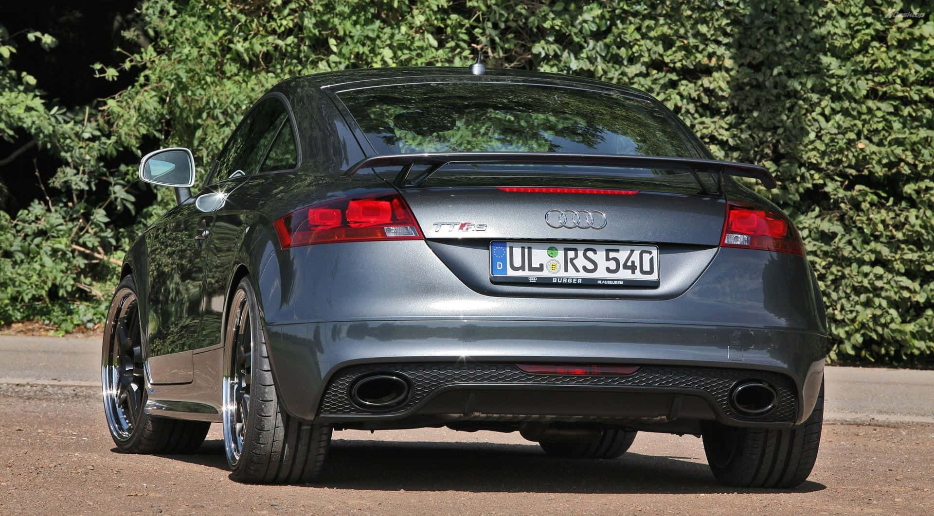 Audi Tt 桌布 壁紙 — 一架型格銀色奧迪TT RS跑車停泊在碎石路上，背景是茂密的綠色樹葉。