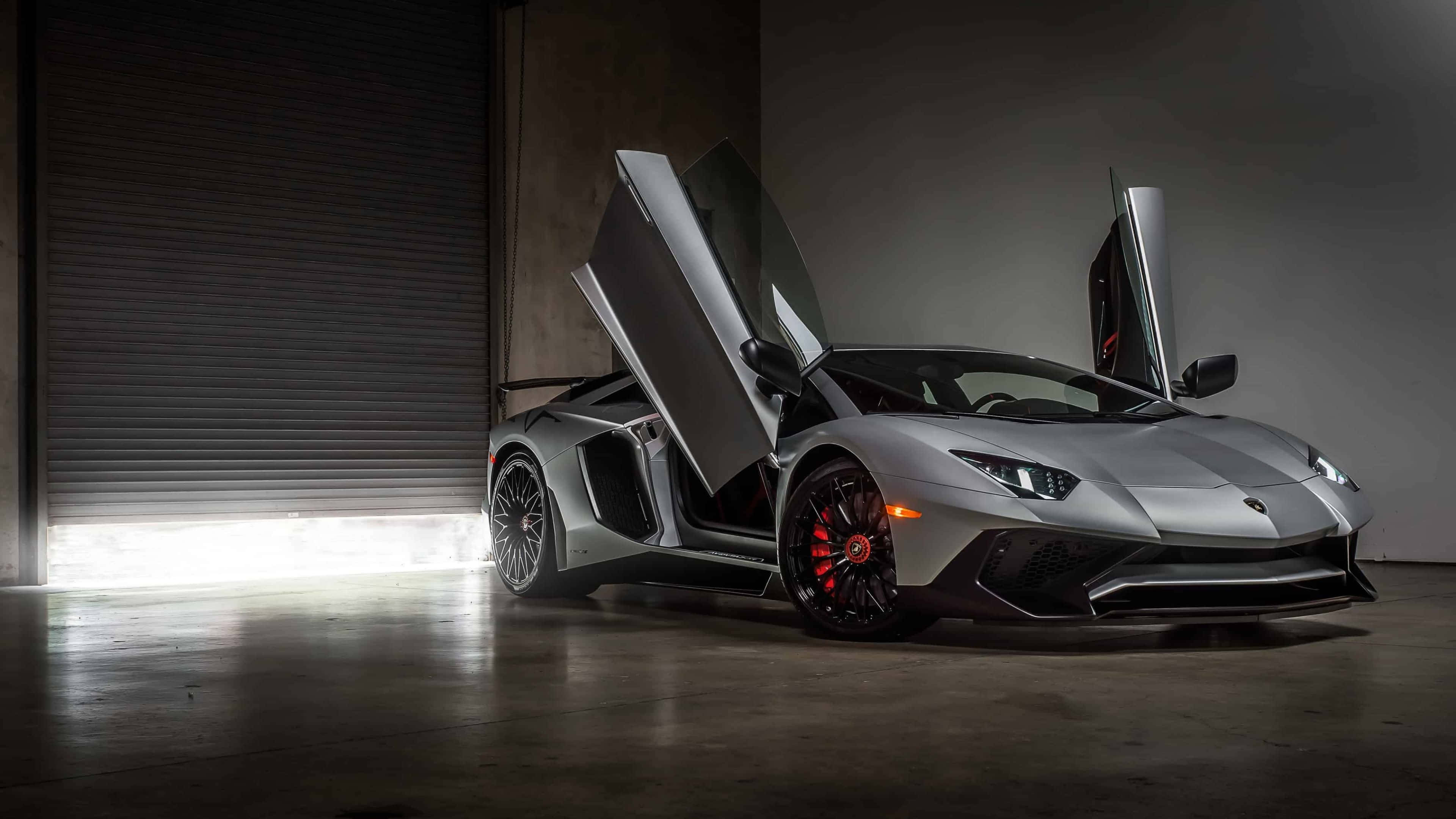 林寶堅尼 4K 桌布 壁紙 — 一架型格銀色林寶堅尼Aventador，車門向上打開，在昏暗的車庫中，被關閉的捲閘門射出的明亮燈光照耀下，顯得格外有氣勢。