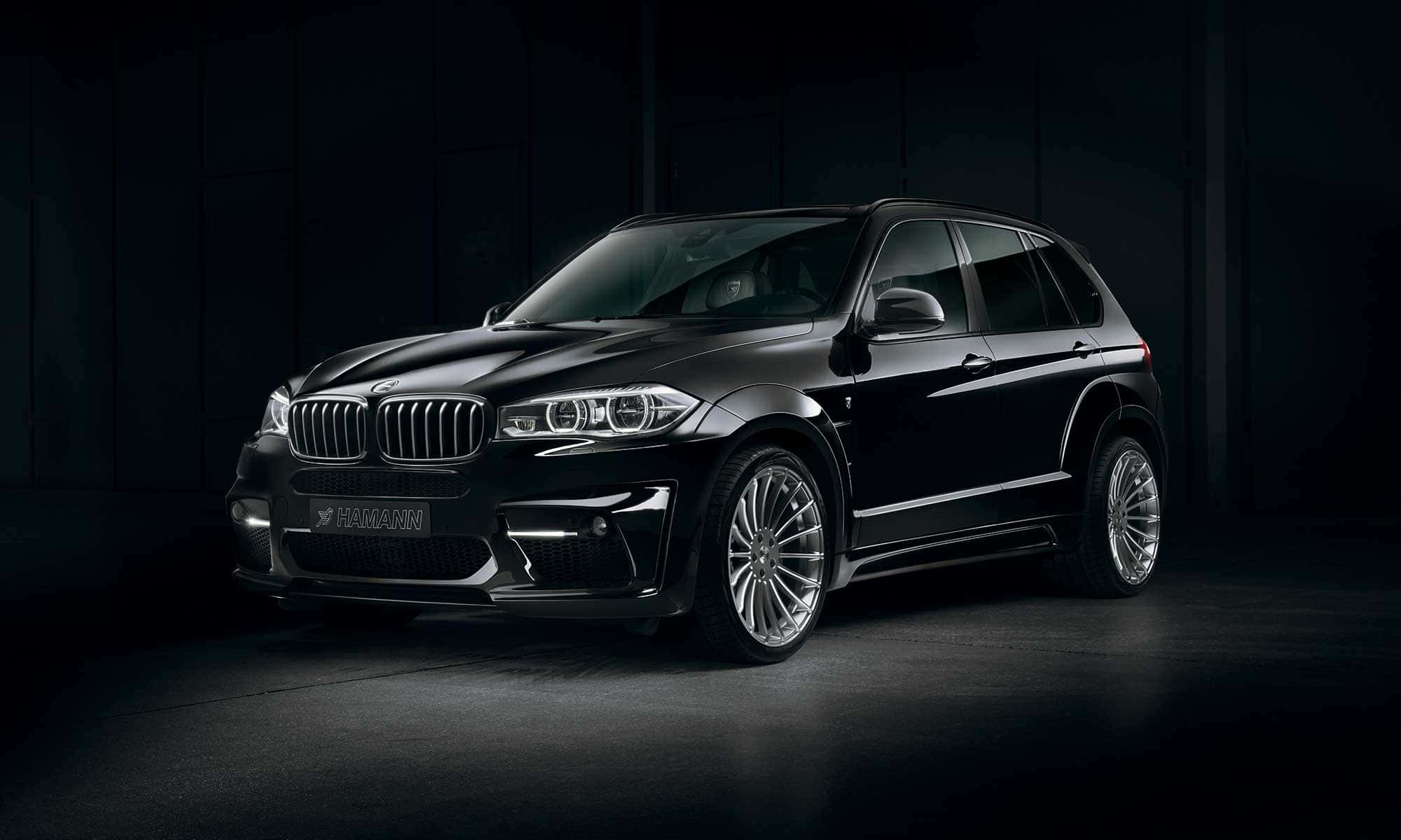 Bmw X5 桌布 壁紙 — 一架型格黑色 Hamann 改裝 BMW X5 SUV 在昏暗工業環境的戲劇性影樓燈光下閃耀。