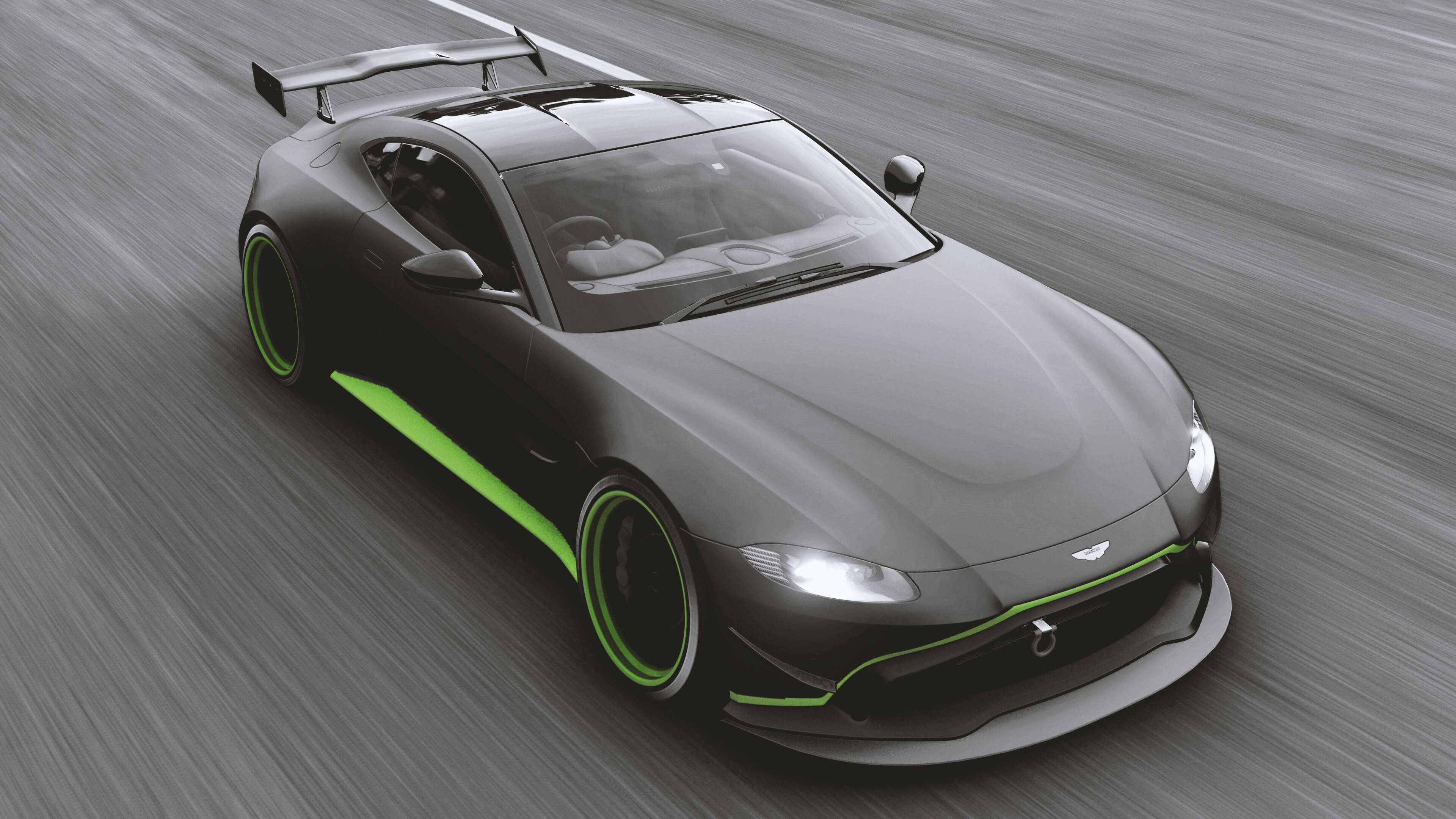 遊戲 桌布 壁紙 — 一架型格黑色Aston Martin跑車，帶有鮮綠色點綴，在模糊的賽道表面上疾馳。