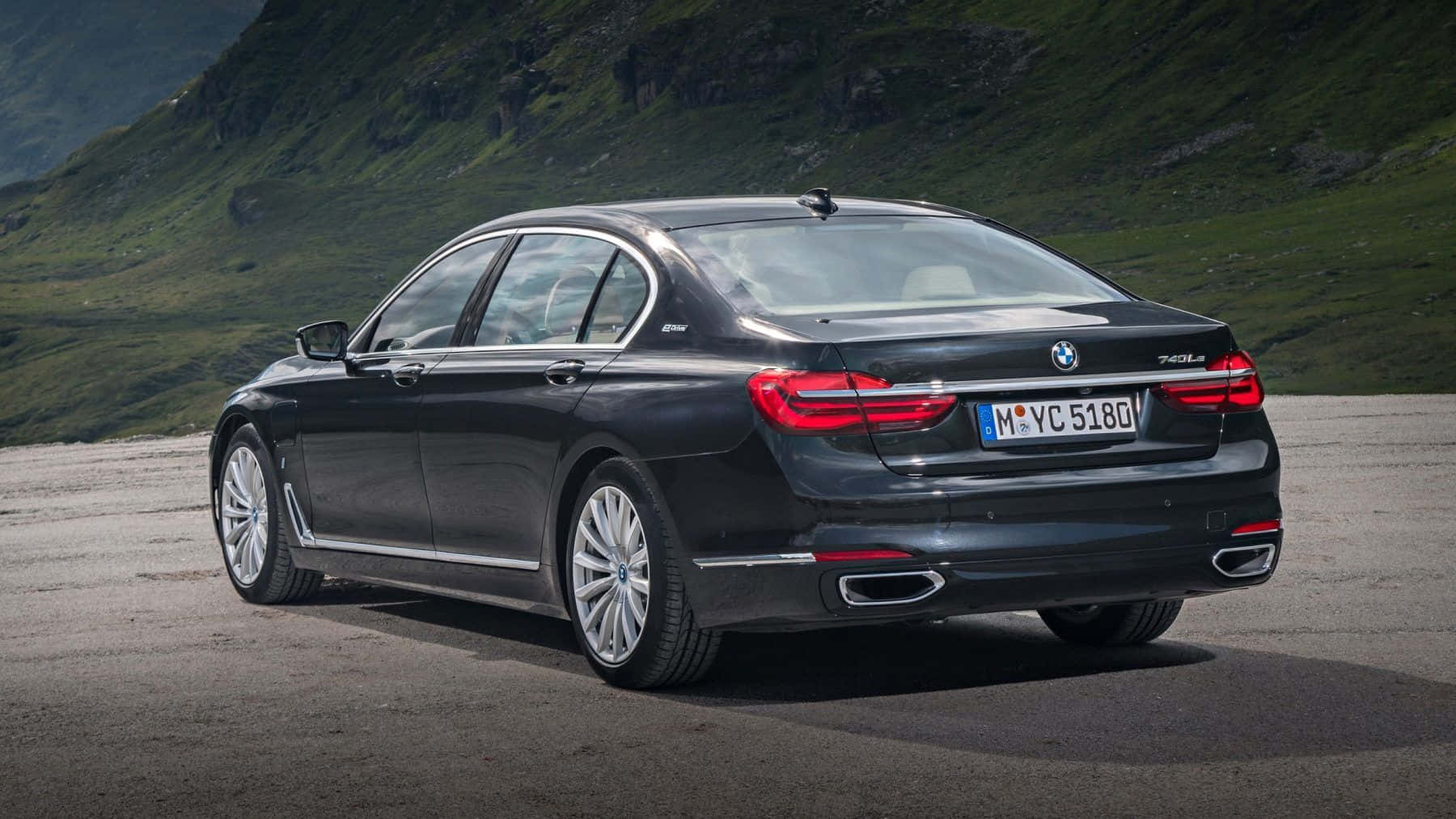 Bmw 7 Series 桌布 壁紙 — 一架型格黑色BMW 740Li房車停泊在碎石路上，背景是翠綠的山巒地帶。