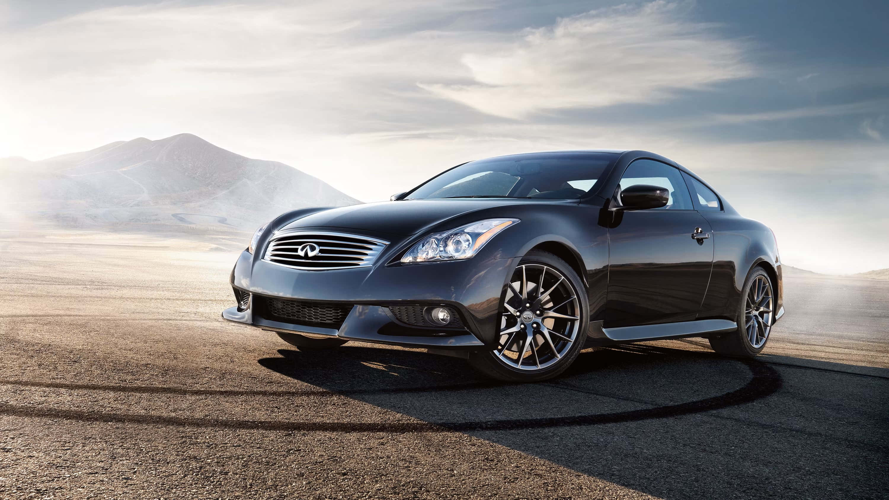 Infiniti Q60 桌布 壁紙 — 一架型格黑色Infiniti轎跑車停泊在沙漠公路上，遠山在陰天下若隱若現。