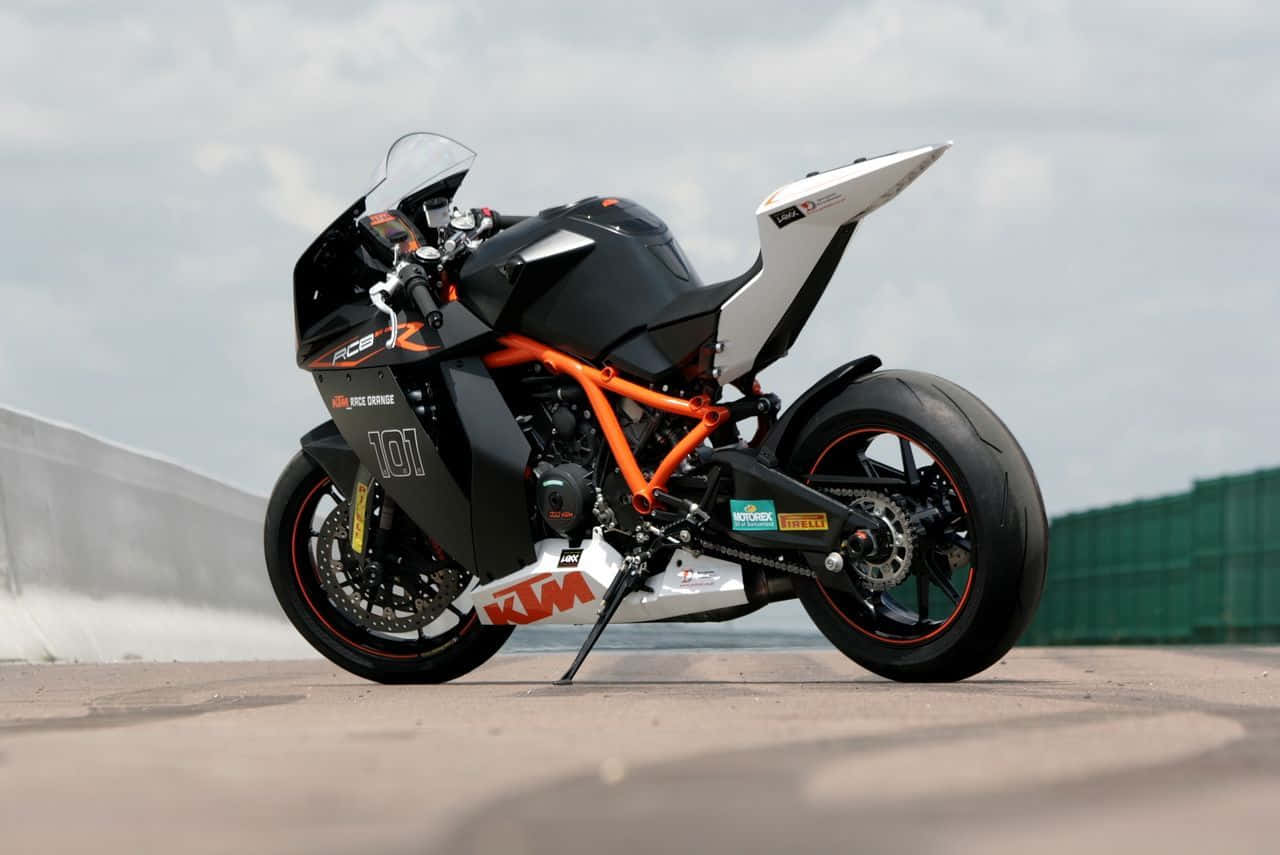 Ktm Bike 桌布 壁紙 — 一架型格黑色橙色KTM RC8R跑車電單車，在陰天下蓄勢待發地停在賽道上。