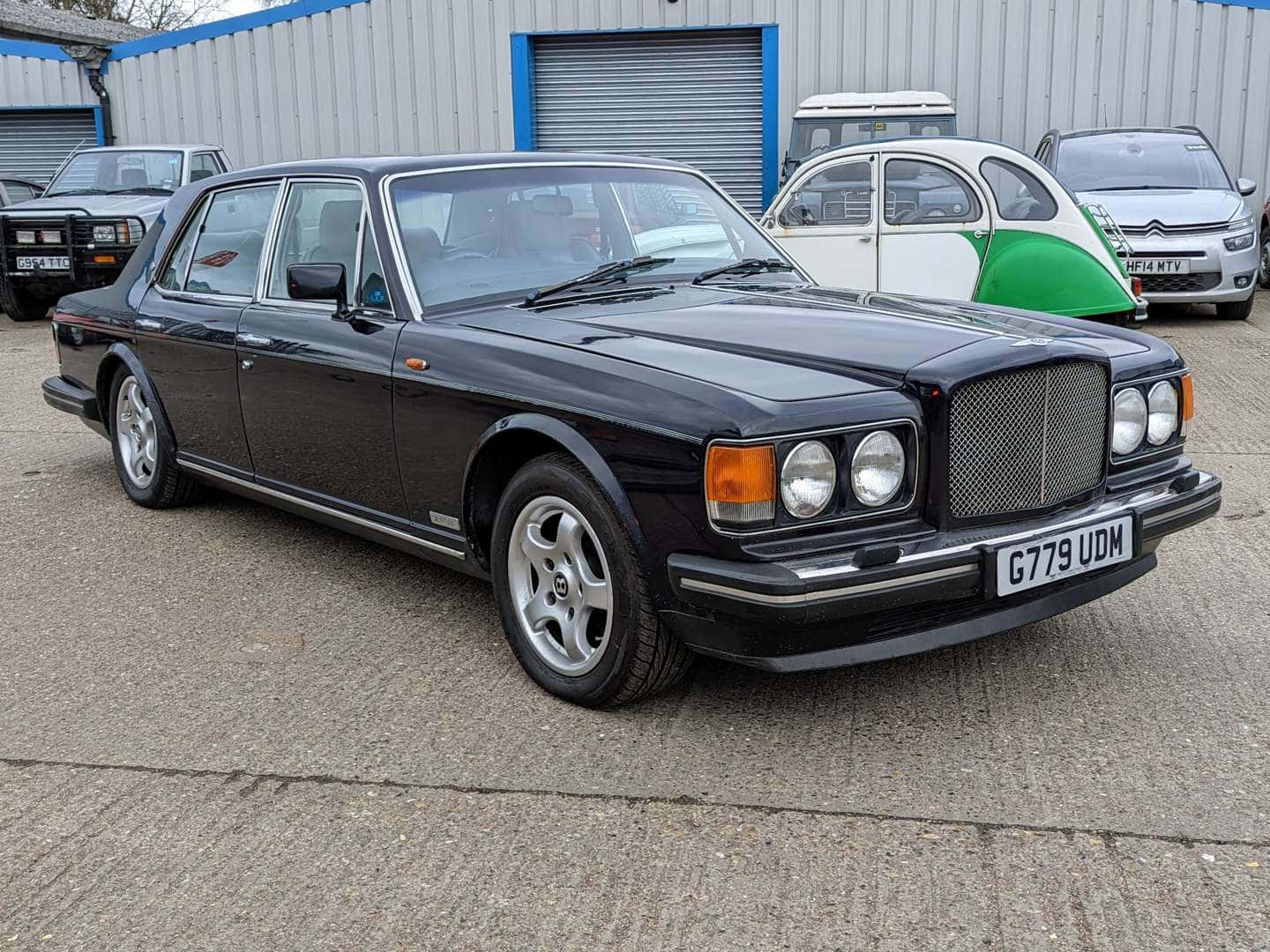 Bentley Eight 桌布 壁紙 — 一架型格黑色賓利 Turbo R 房車停在混凝土上，背景有其他經典汽車。