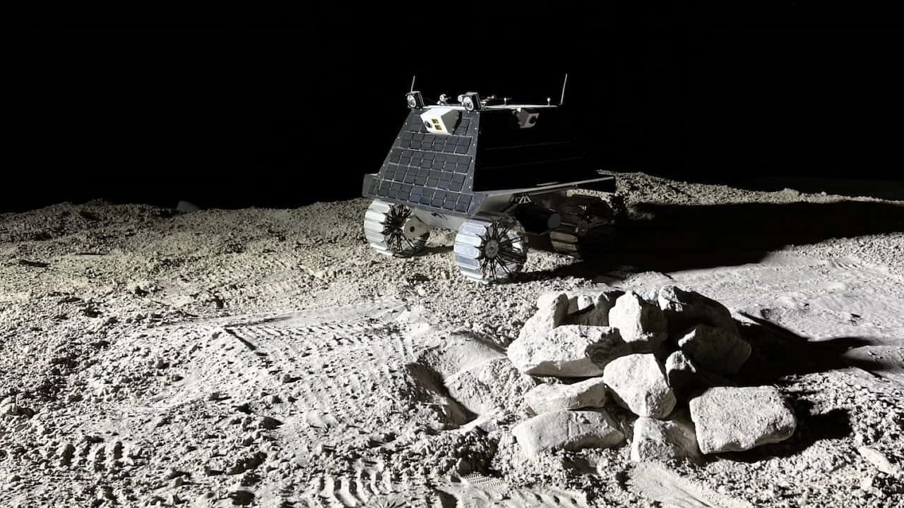 Lunar Rover 桌布 壁紙 — 一架堅固的月球車配備太陽能板，在漆黑的天空下於岩石密佈的月球表面行駛。