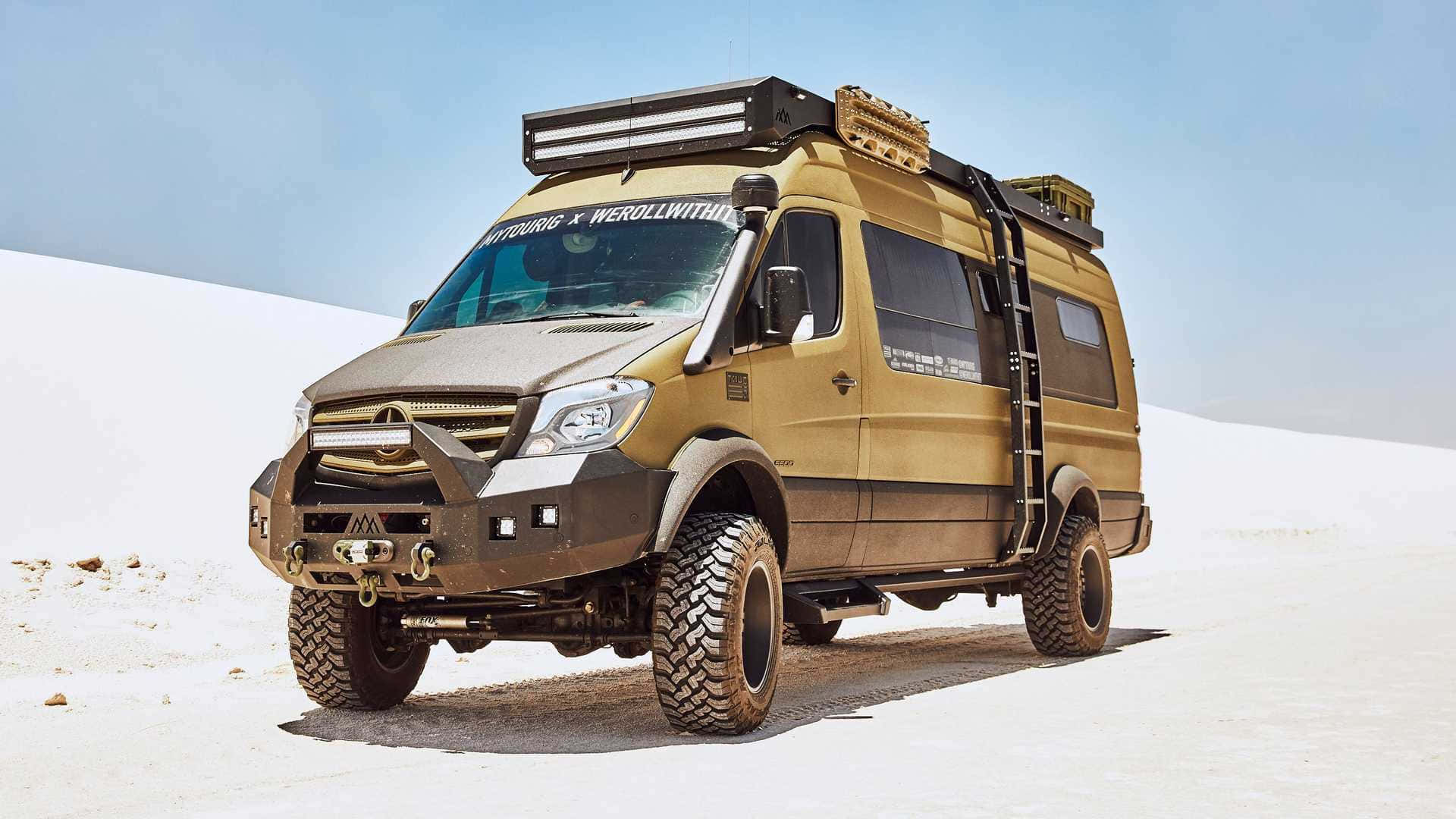 Mercedes Benz Sprinter 桌布 壁紙 — 一架堅固的金啡色越野露營車，配備特大輪胎和車頂行李架，在晴朗藍天下矗立於廣闊的白色鹽灘上。