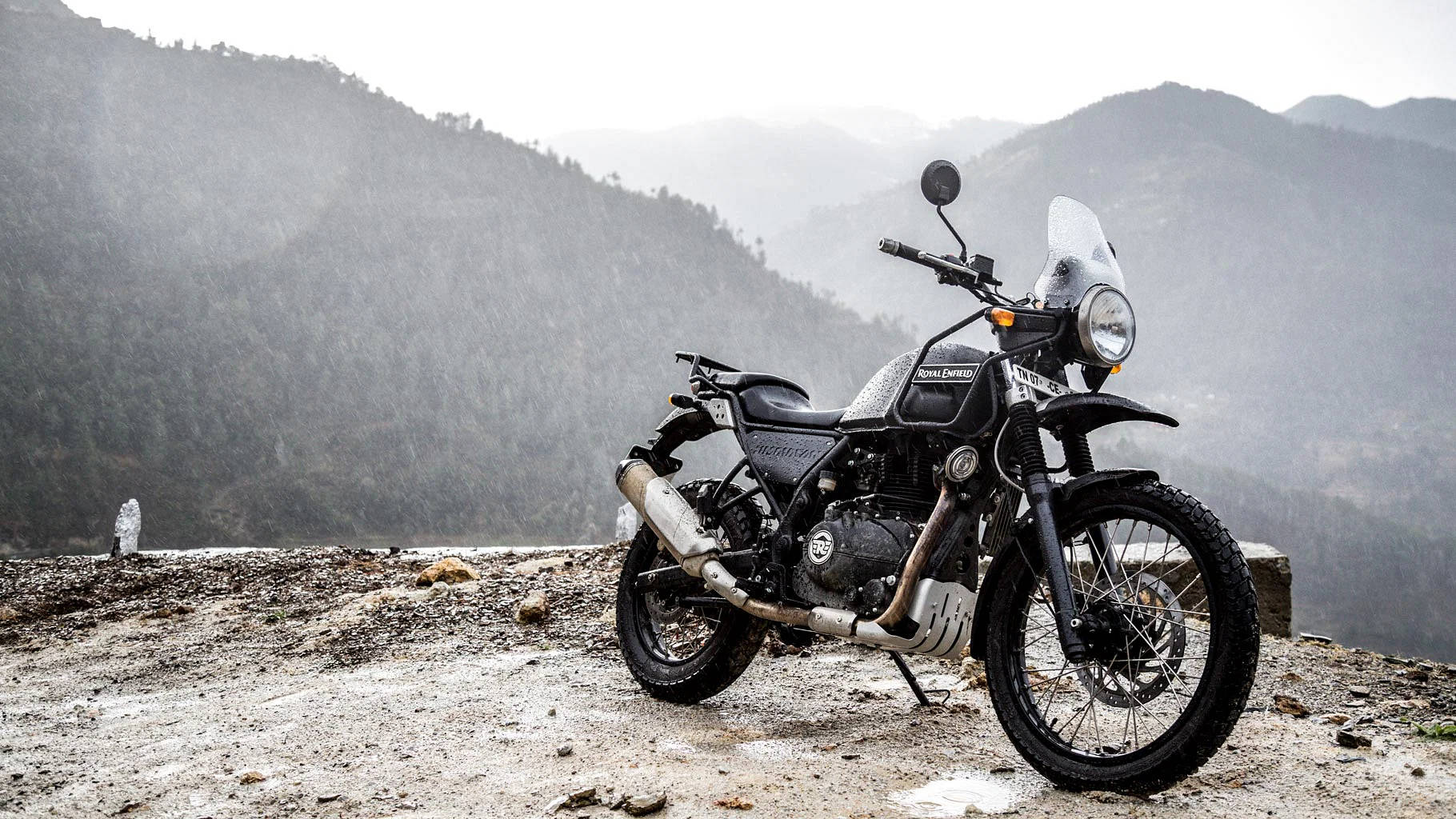 自行車 桌布 壁紙 — 一架堅固的黑色 Royal Enfield 電單車停泊在霧氣瀰漫的山景觀景點，遠處的森林山峰逐漸消失。