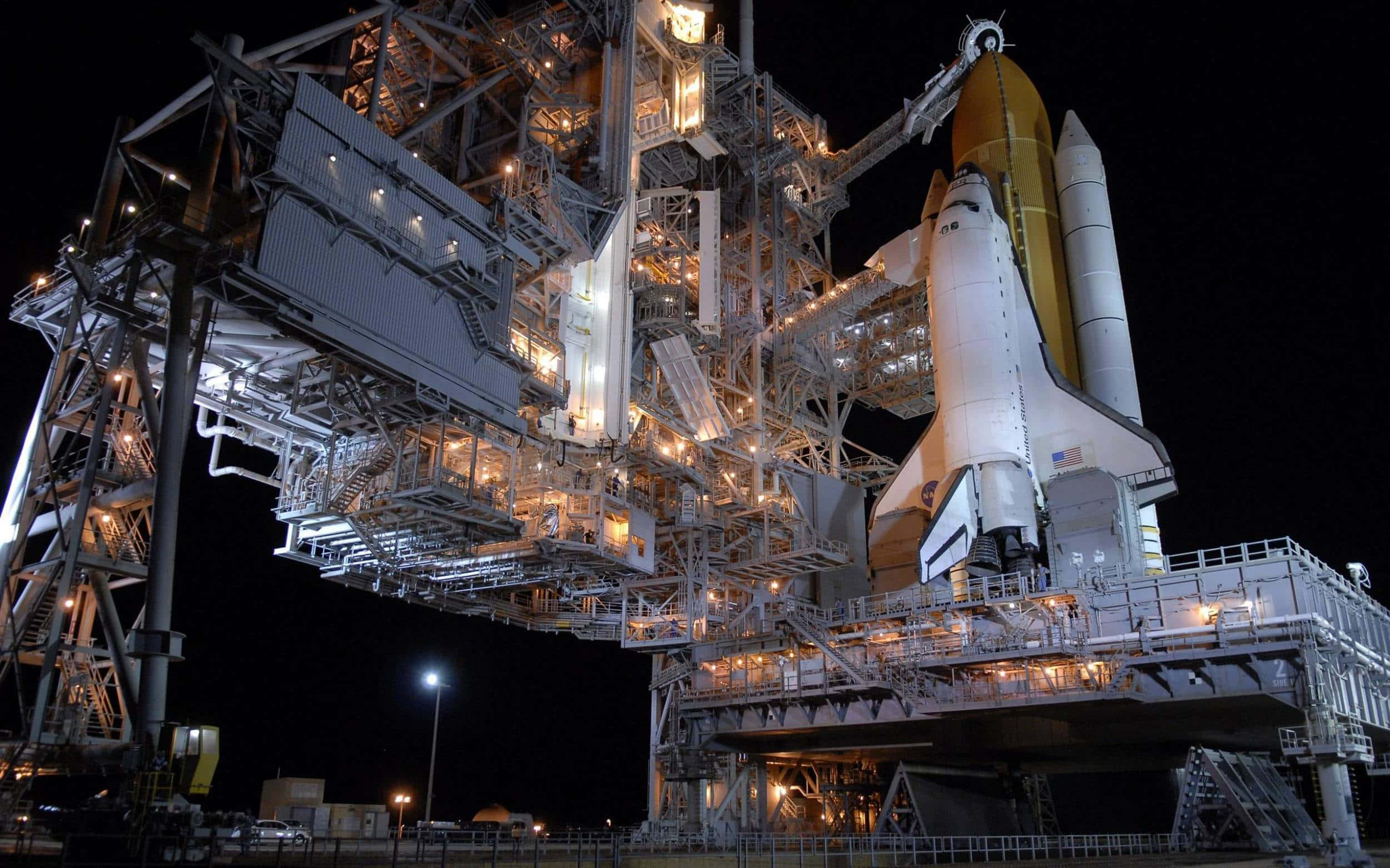 nasa 桌布 壁紙 — 一架太空穿梭機在夜間停泊在發射台上，被人工燈光照亮，襯托著漆黑的天空。