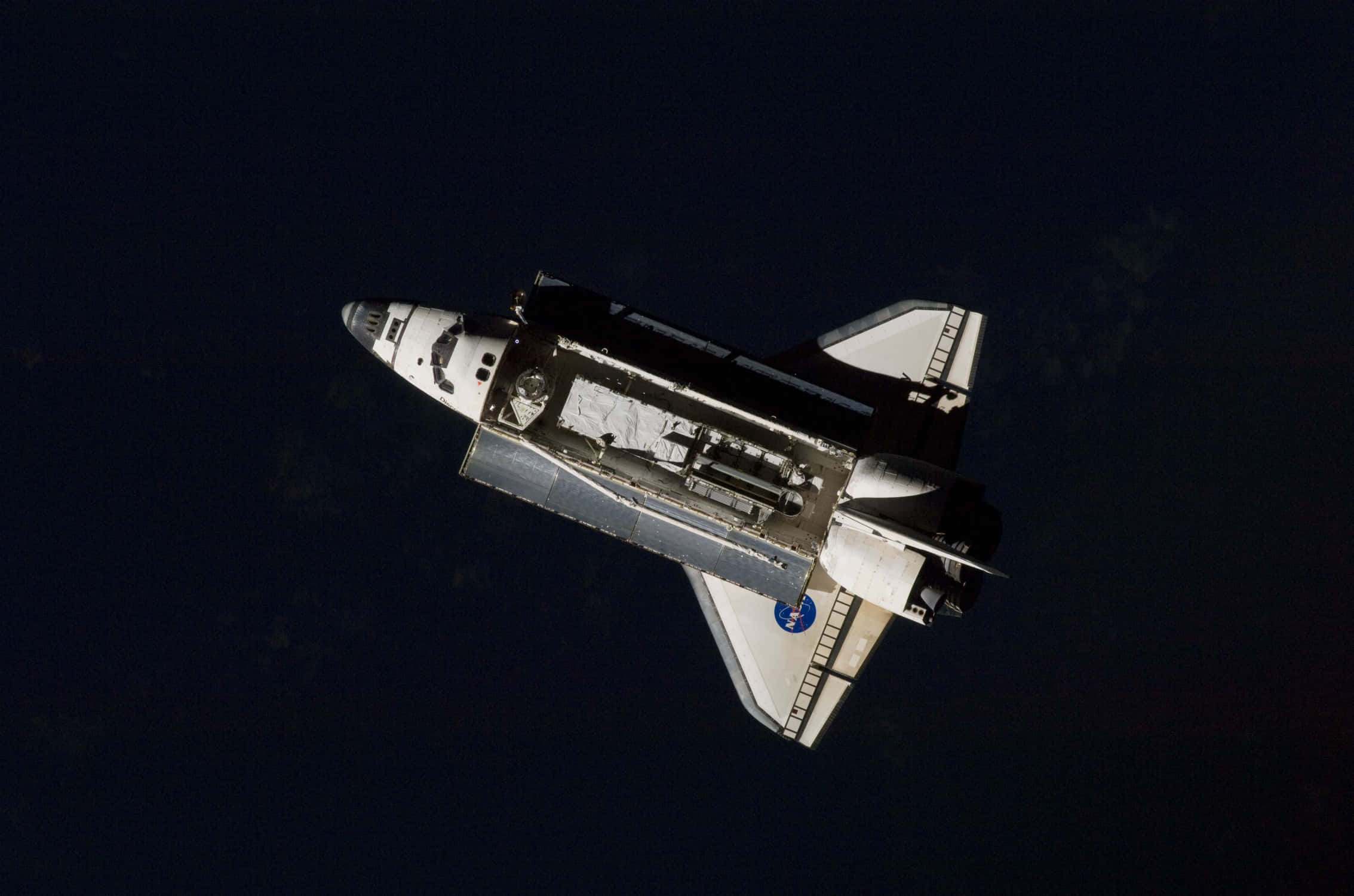 Spacecraft 桌布 壁紙 — 一架太空穿梭機在太空的黑暗中滑行，下方可見地球彎曲的地平線。