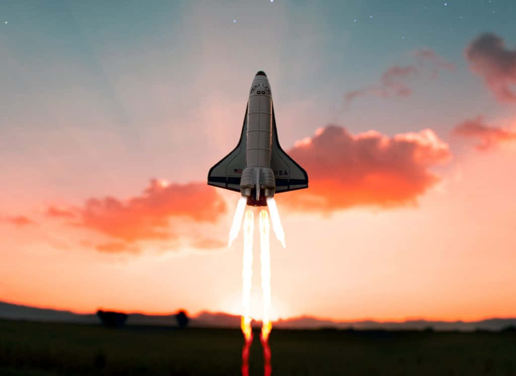 火箭 桌布 壁紙 — 一架太空穿梭機在暮色中升空，拖著熾熱的尾焰，映襯著橙色的雲層和遠山。