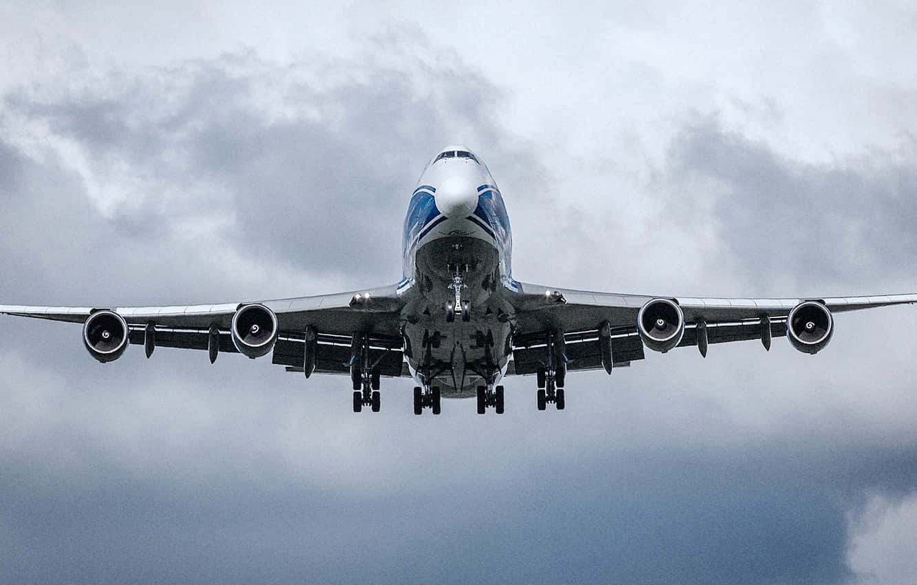Jumbo Jets 桌布 壁紙 — 一架巨型珍寶客機正面朝向戲劇性的多雲天空下降，起落架已放下。