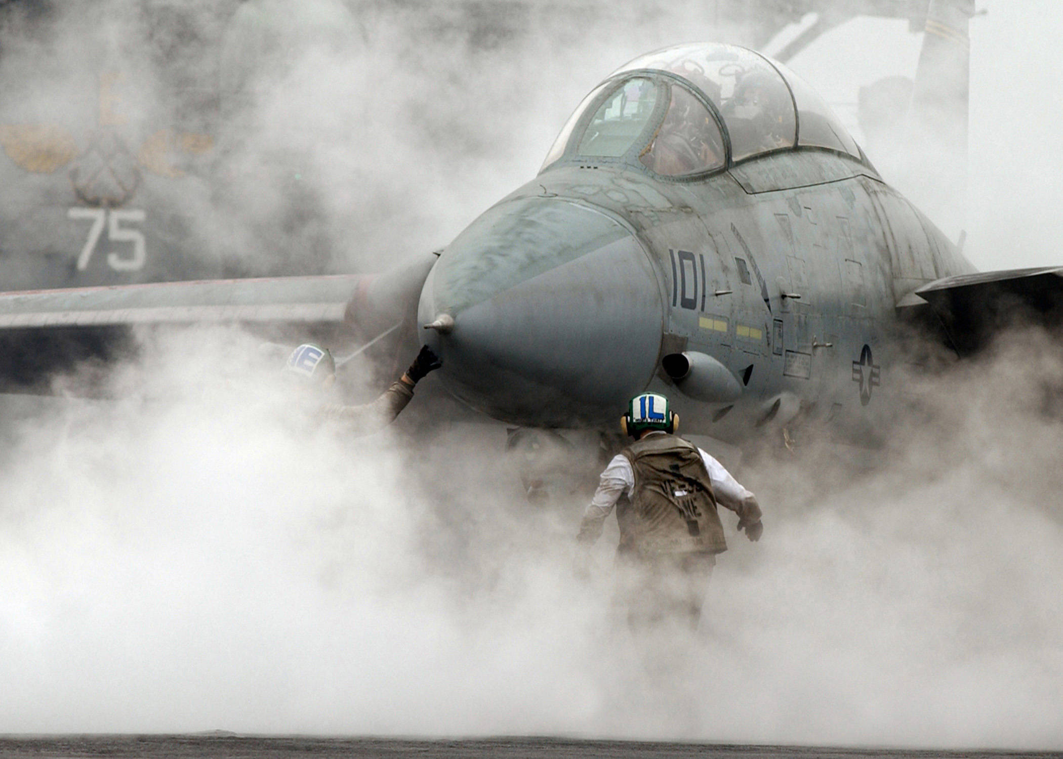飛機 桌布 壁紙 — 一架戰鬥機在航空母艦甲板上噴出煙霧，機組人員正在引導它。