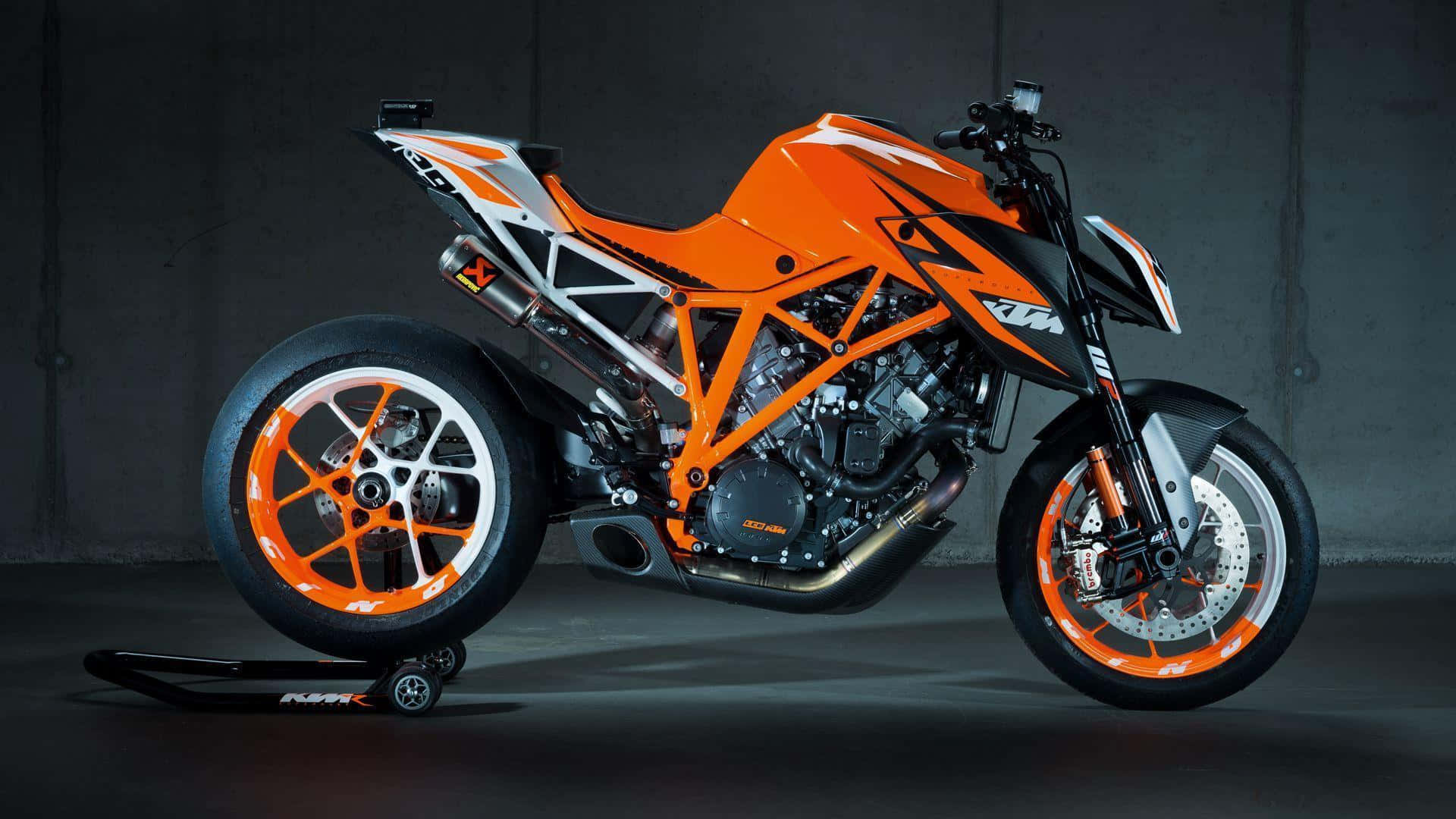 Ktm Bike 桌布 壁紙 — 一架搶眼的橙色和黑色KTM電單車，帶有外露車架和定制輪圈，停放在支架上，背景是深色混凝土牆。