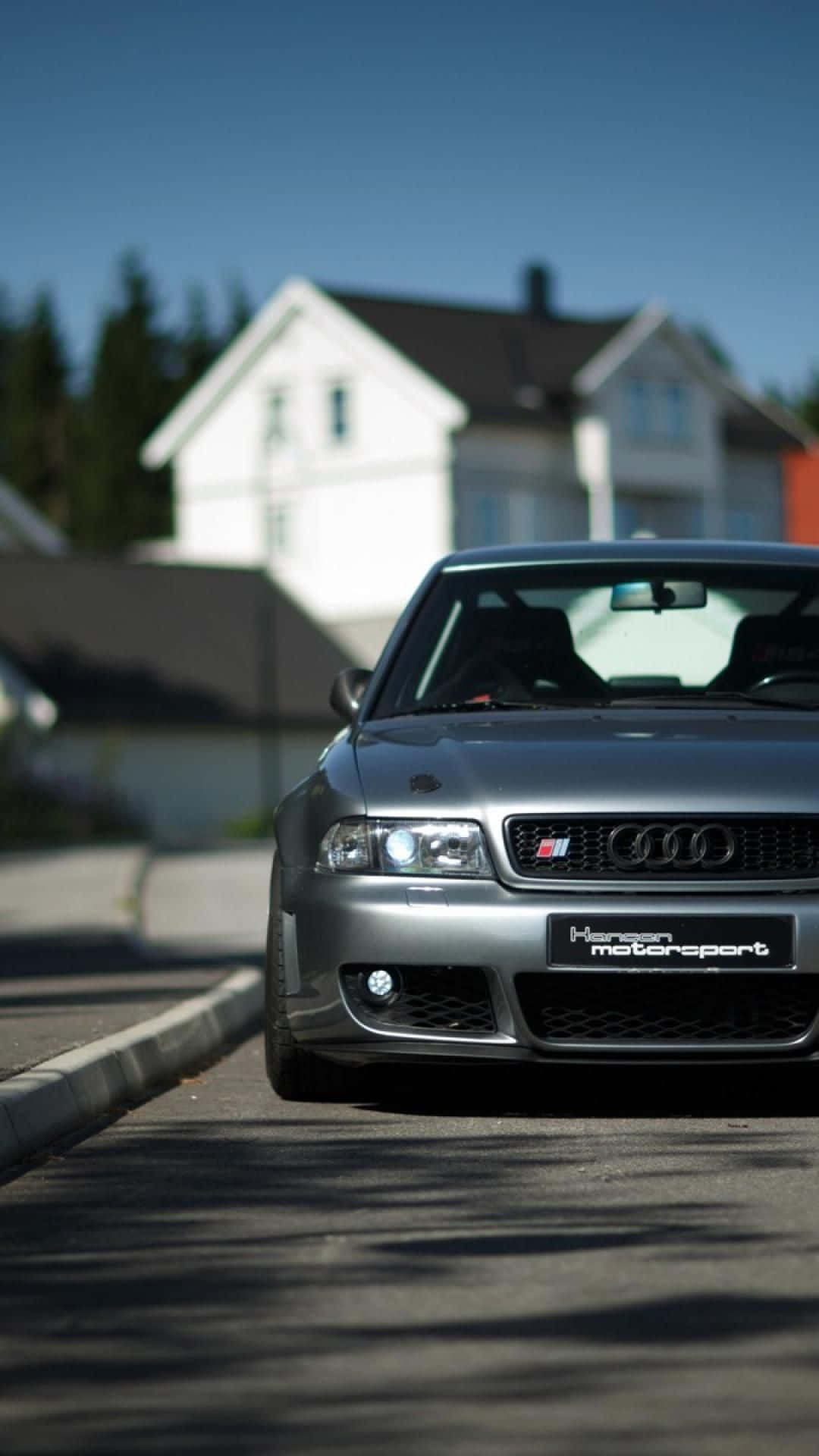 Audi S4 桌布 壁紙 — 一架時尚嘅銀色 Audi 跑車停泊喺陽光普照嘅住宅街道上，背景係一間白色房屋。