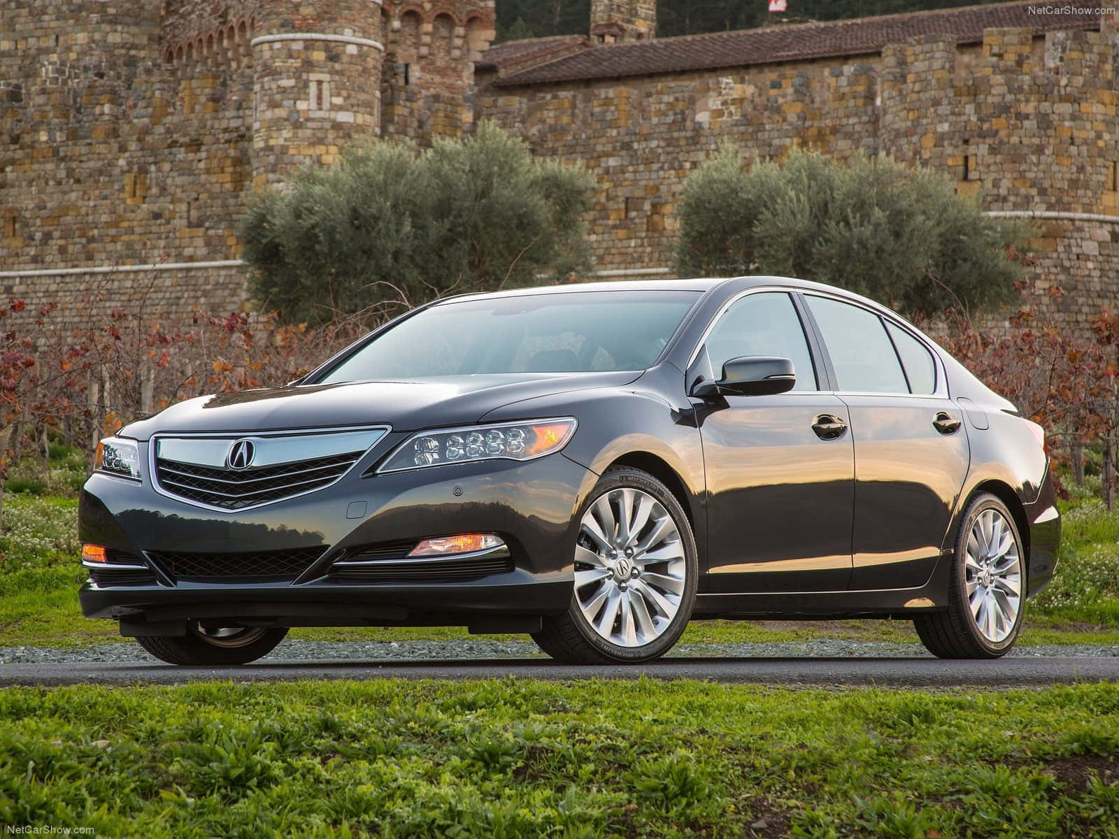 Acura Rlx 桌布 壁紙 — 一架時尚深灰色Acura房車停泊在碎石路上，前面係一座鄉村風格嘅石城堡，周圍有橄欖樹同秋天嘅樹葉。