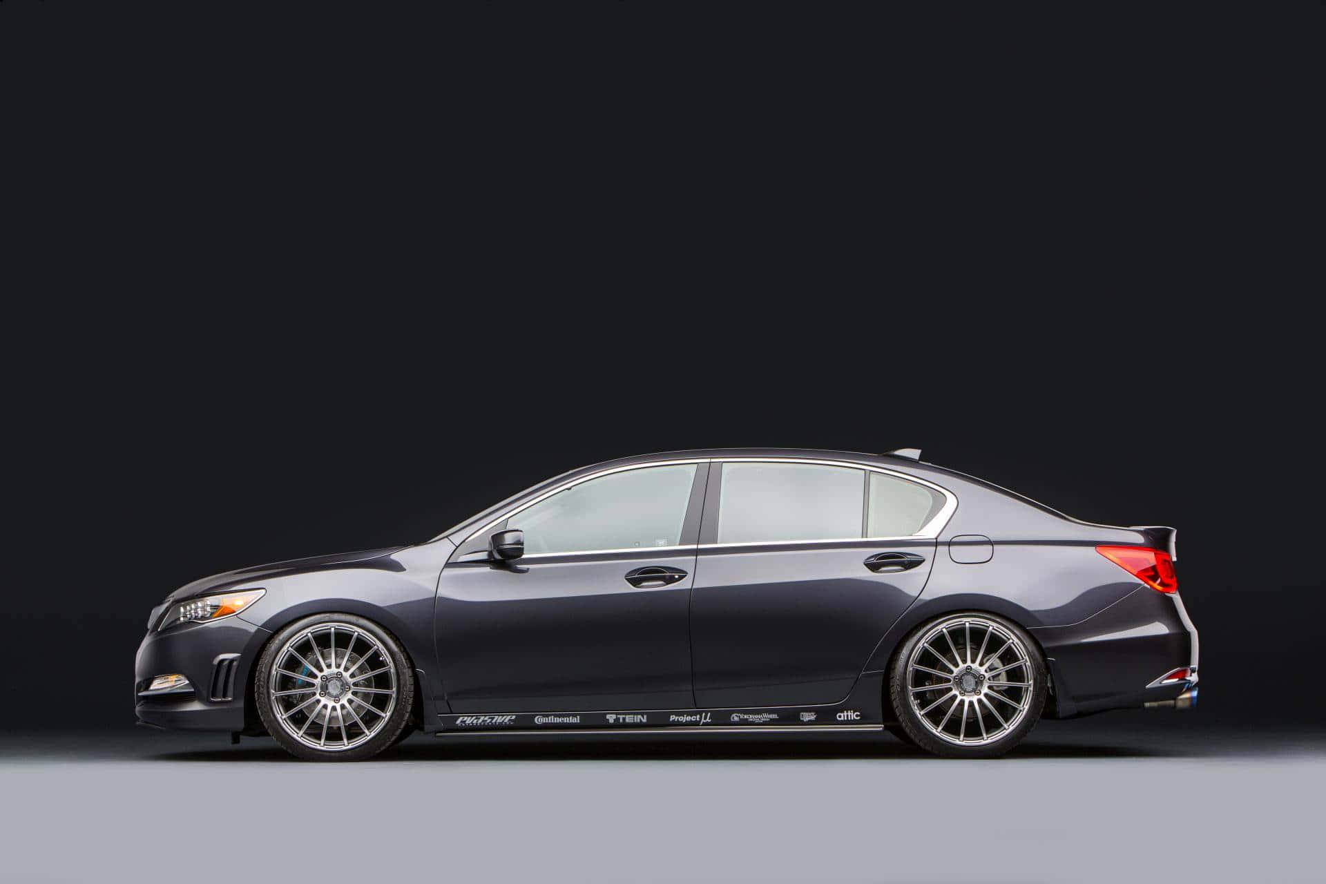 Acura Rlx 桌布 壁紙 — 一架時尚深灰色改裝房車，配備訂製輪圈和側面貼紙，以側面輪廓呈現，背景為極簡黑灰工作室背景。