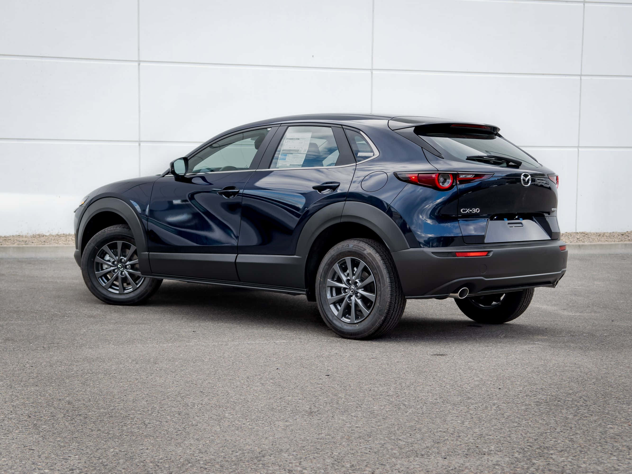 Mazda Cx-30 桌布 壁紙 — 一架時尚深藍色Mazda CX-30 SUV停泊在瀝青路上，背景是簡約的白色瓷磚牆。