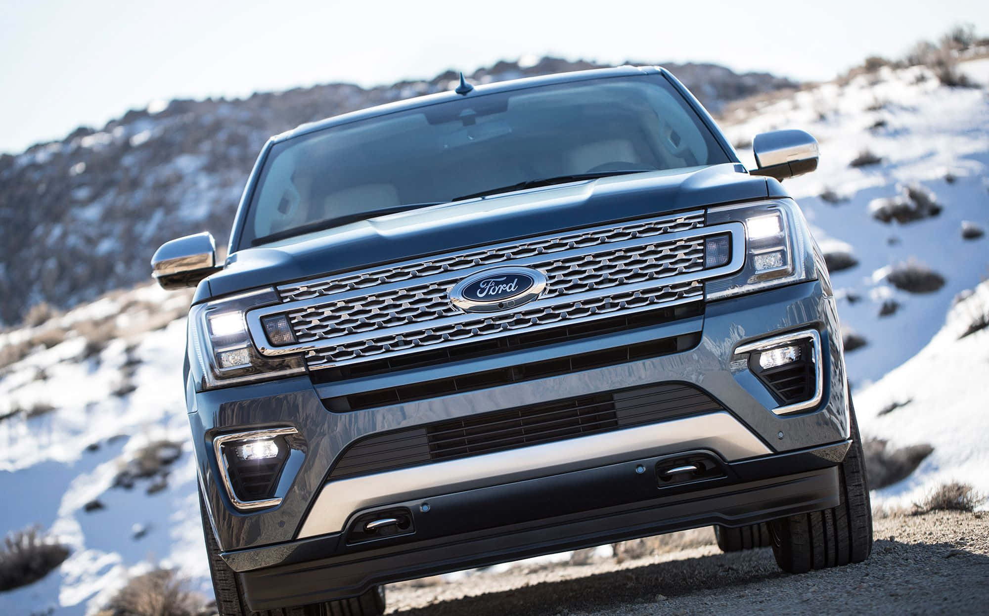 Ford Expedition 桌布 壁紙 — 一架時尚深藍色福特Explorer SUV停泊在積雪的山路上，背景係崎嶇嘅地形。