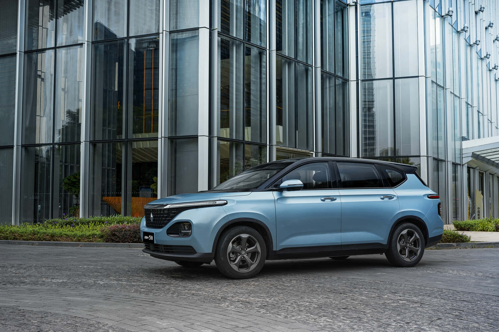 Baojun 桌布 壁紙 — 一架時尚淺藍色SUV停泊在現代玻璃建築前的鵝卵石街道上。