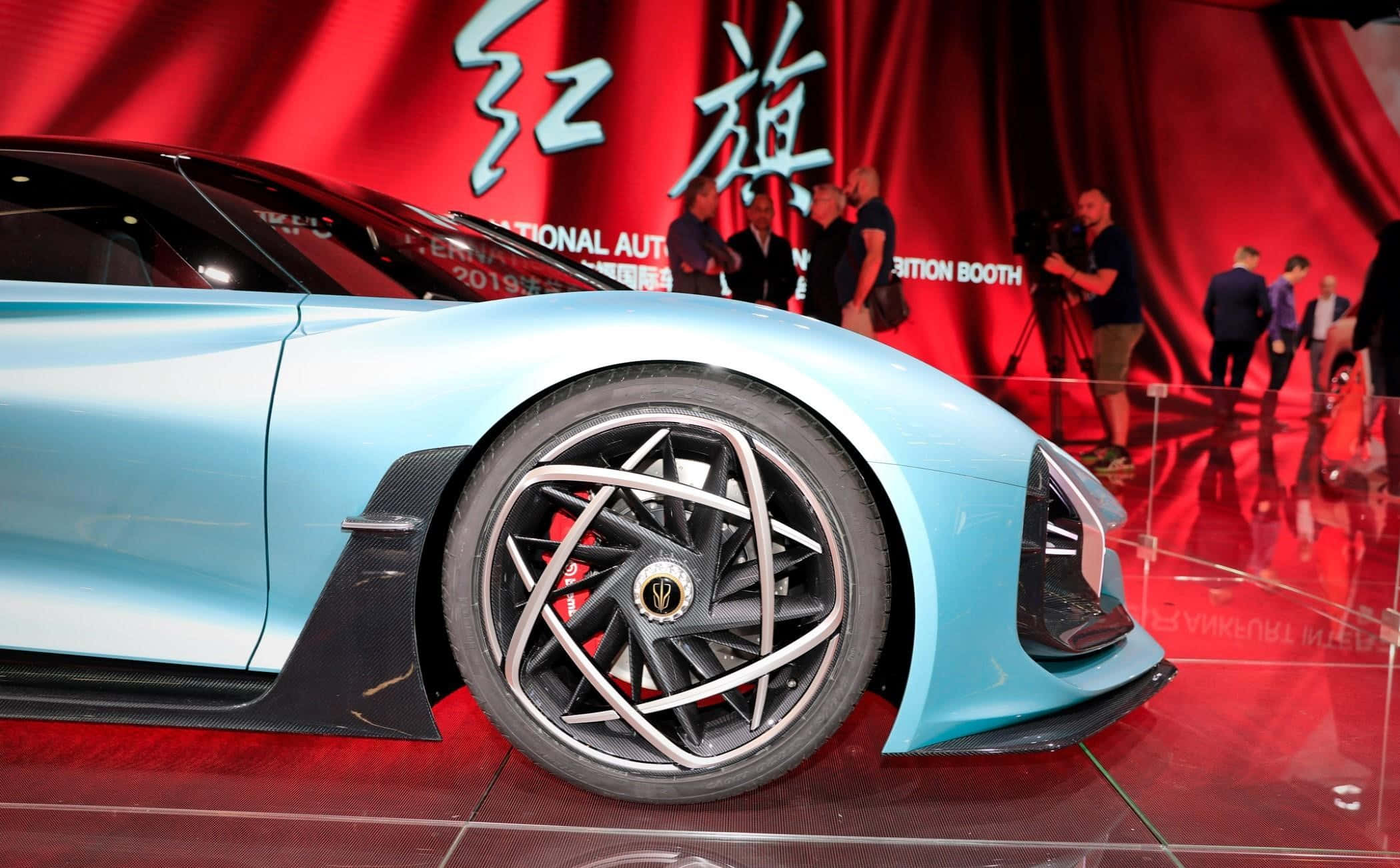 Hongqi 桌布 壁紙 — 一架時尚淺藍色跑車，配以精緻車輪設計，在車展的亮紅色展台上展示。
