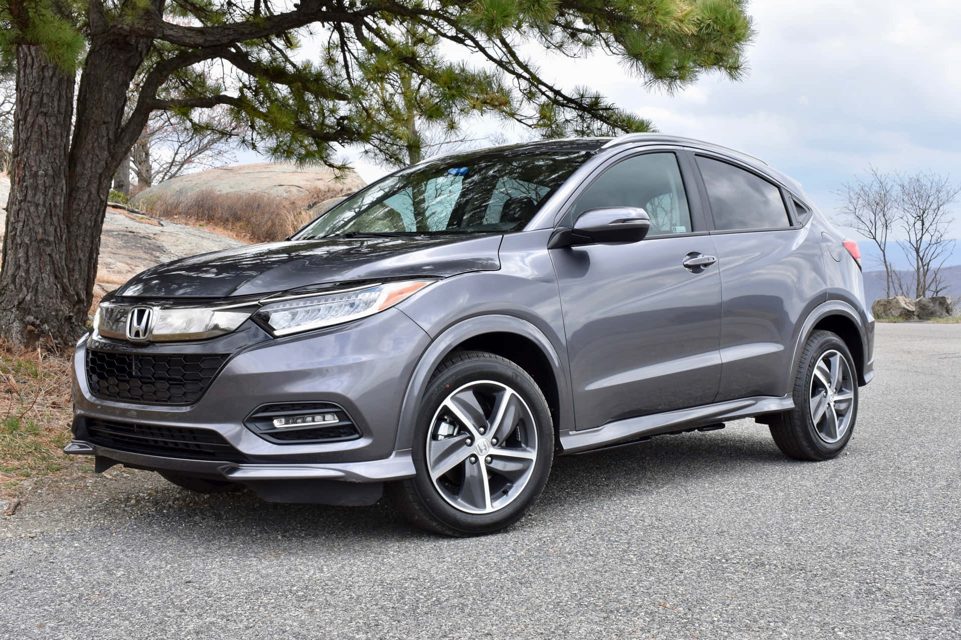 Honda Hr-v 桌布 壁紙 — 一架時尚灰色本田 HR-V SUV 停泊在松樹下的碎石路上，背景是岩石丘陵。