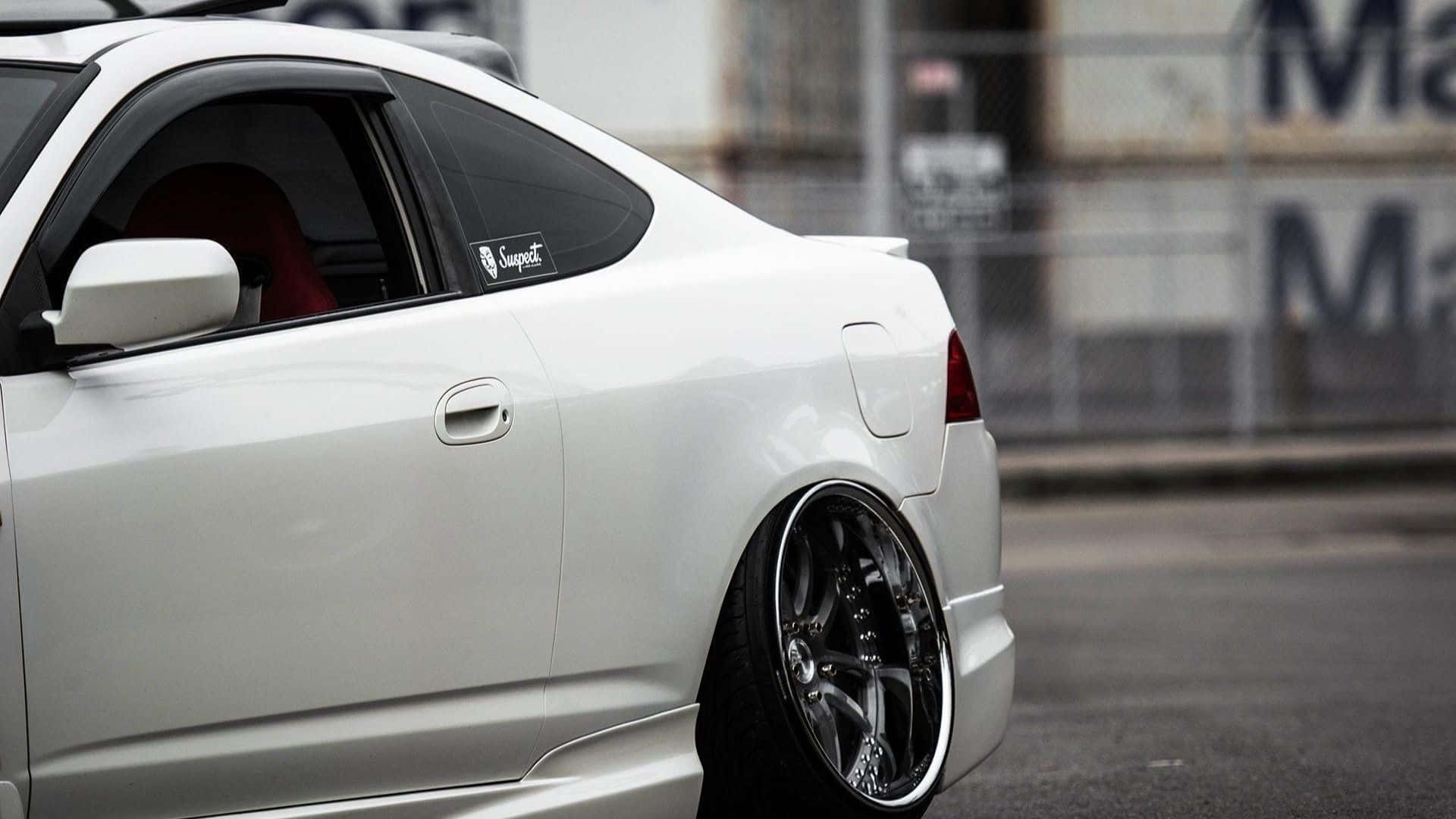 Rsx Type-s 桌布 壁紙 — 一架時尚白色跑車配備訂製黑色輪圈，停泊在模糊工業背景的都市街道上。