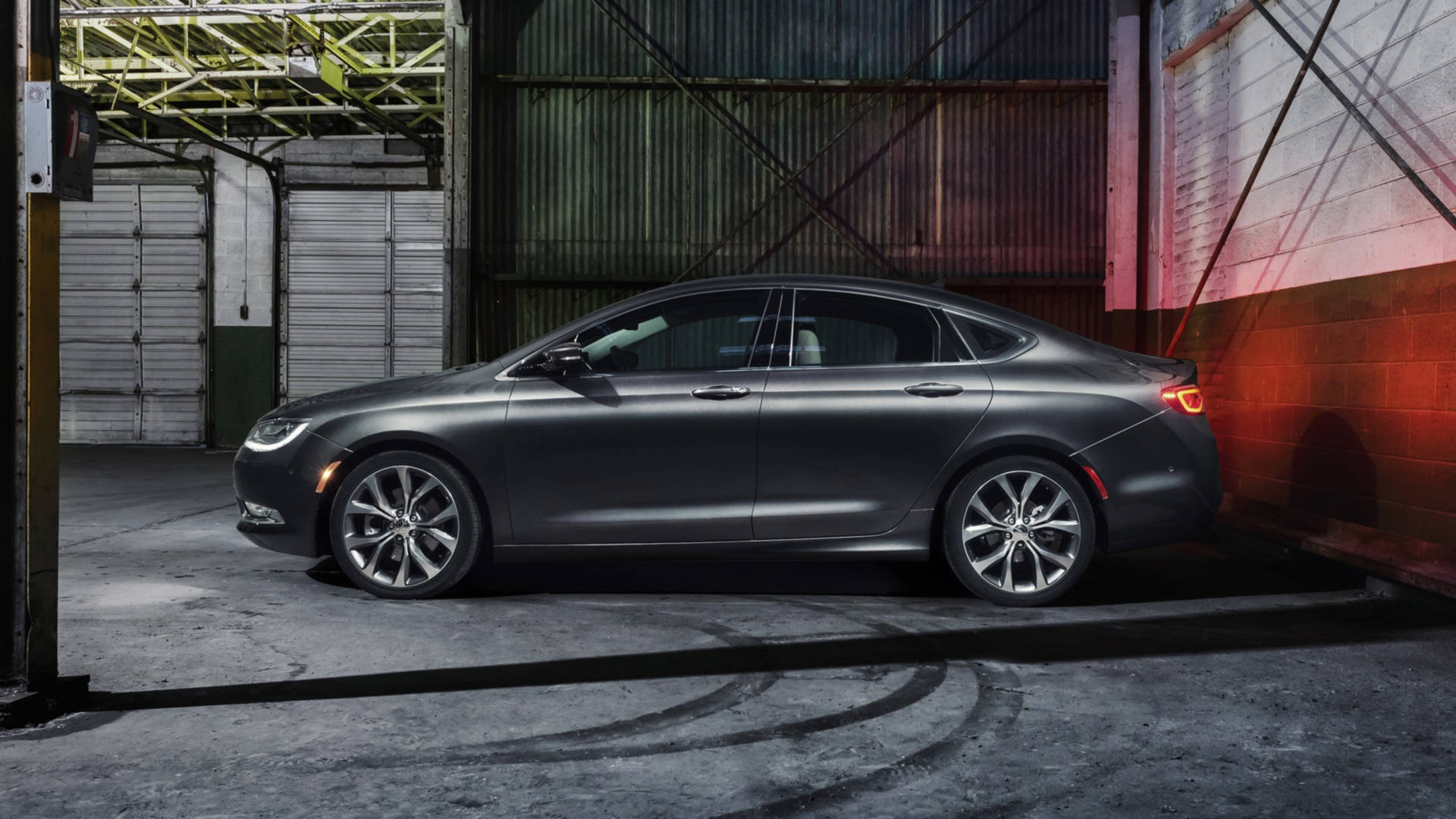 2015 Chrysler 200 S 壁紙 — 一架時尚的啞光灰色轎車停放在粗糙的工業車庫中，紅色牆壁燈光投射出戲劇性的陰影。