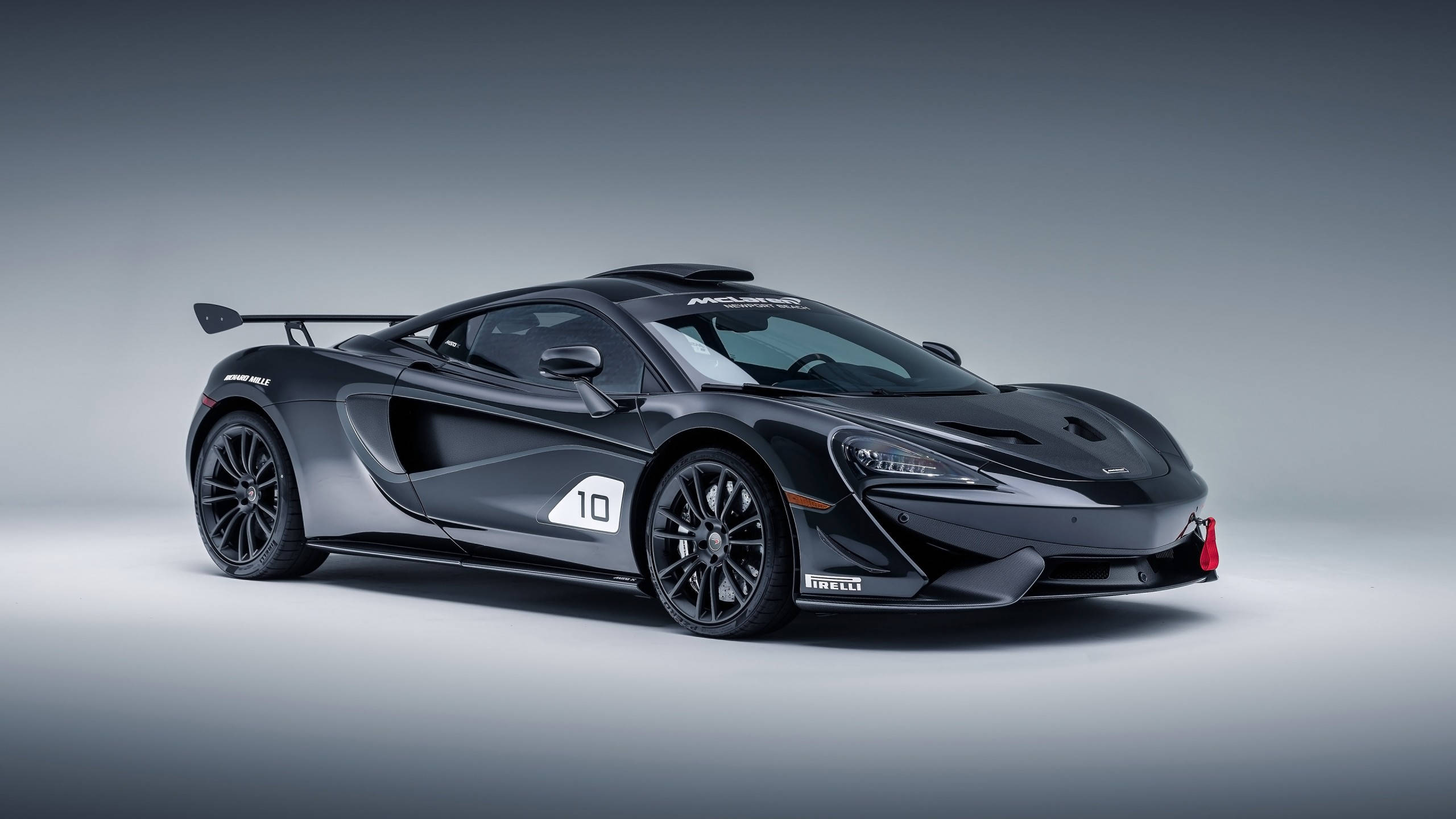 HD Car 桌布 壁紙 — 一架時尚的啞光黑色McLaren 650S GT3賽車，帶有10號和Pirelli品牌標誌，擺放在漸變灰色工作室背景前。