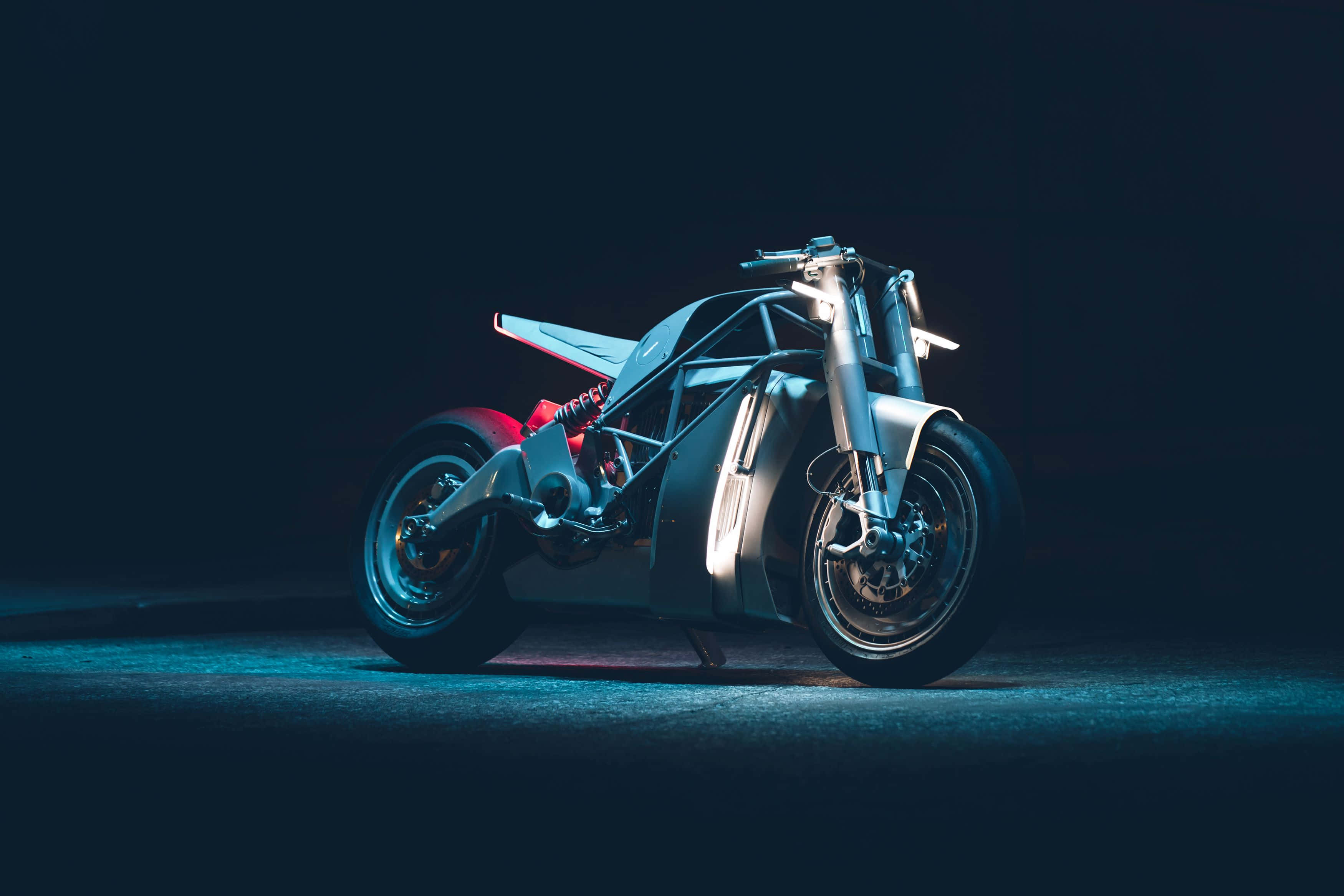 Electric Bike 桌布 壁紙 — 一架時尚的未來電單車在黑暗的攝影棚背景下，在戲劇性的藍色燈光下發光。