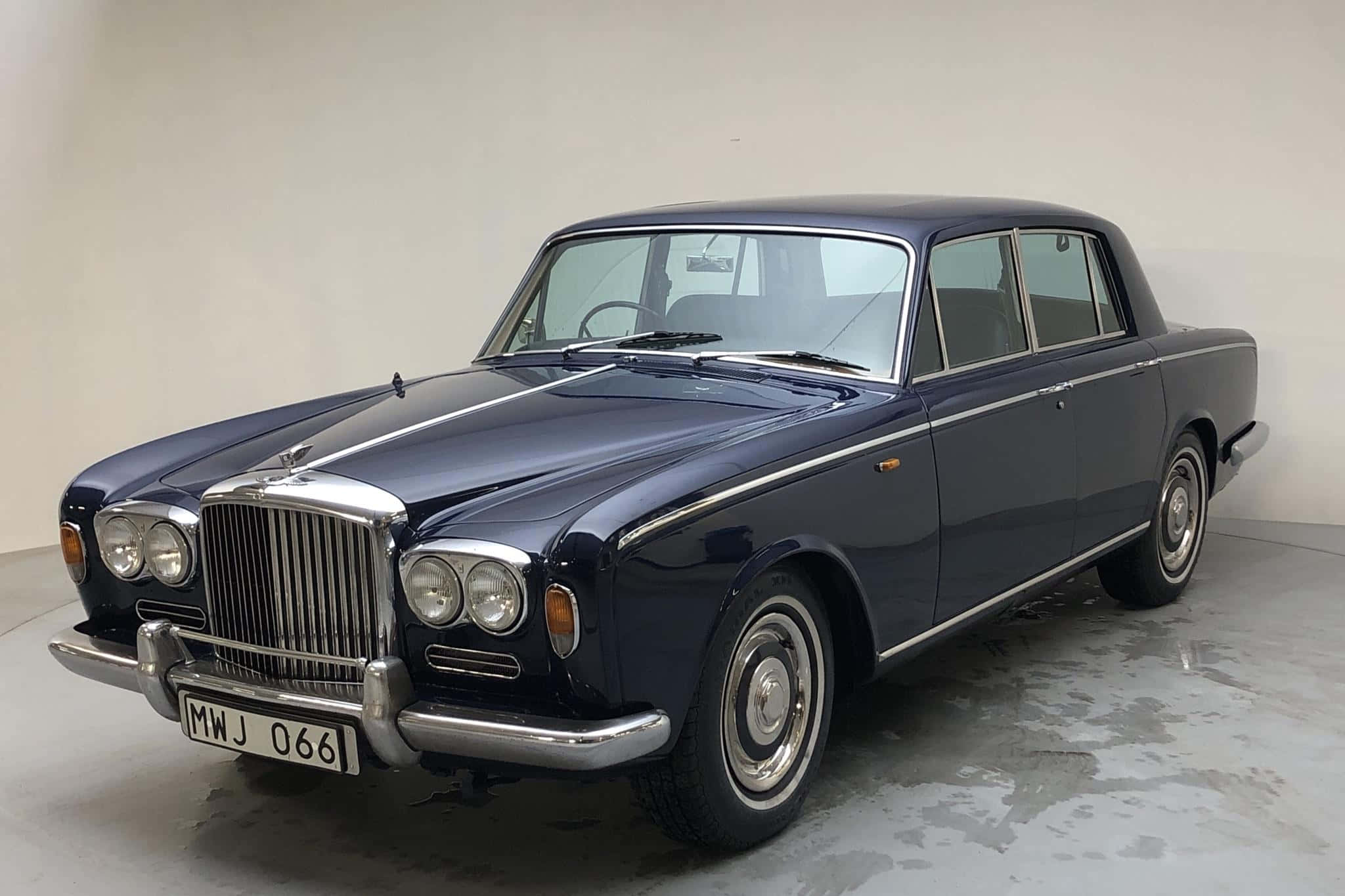 Bentley T2 桌布 壁紙 — 一架時尚的海軍藍色復古賓利轎車，帶有鍍鉻裝飾和經典格柵，矗立在簡約的攝影棚空間中。