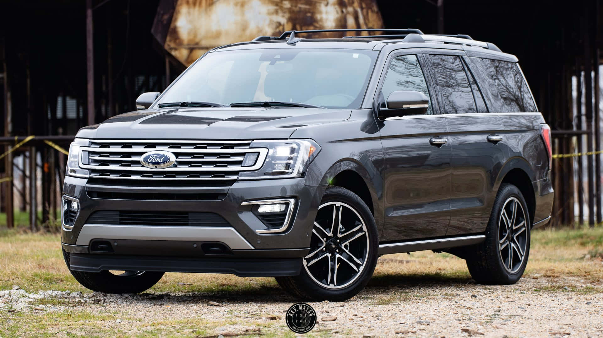Ford Expedition 桌布 壁紙 — 一架時尚的深灰色福特Expedition SUV停泊在碎石路上，前面是一座質樸的穀倉，帶有風化的木牆。