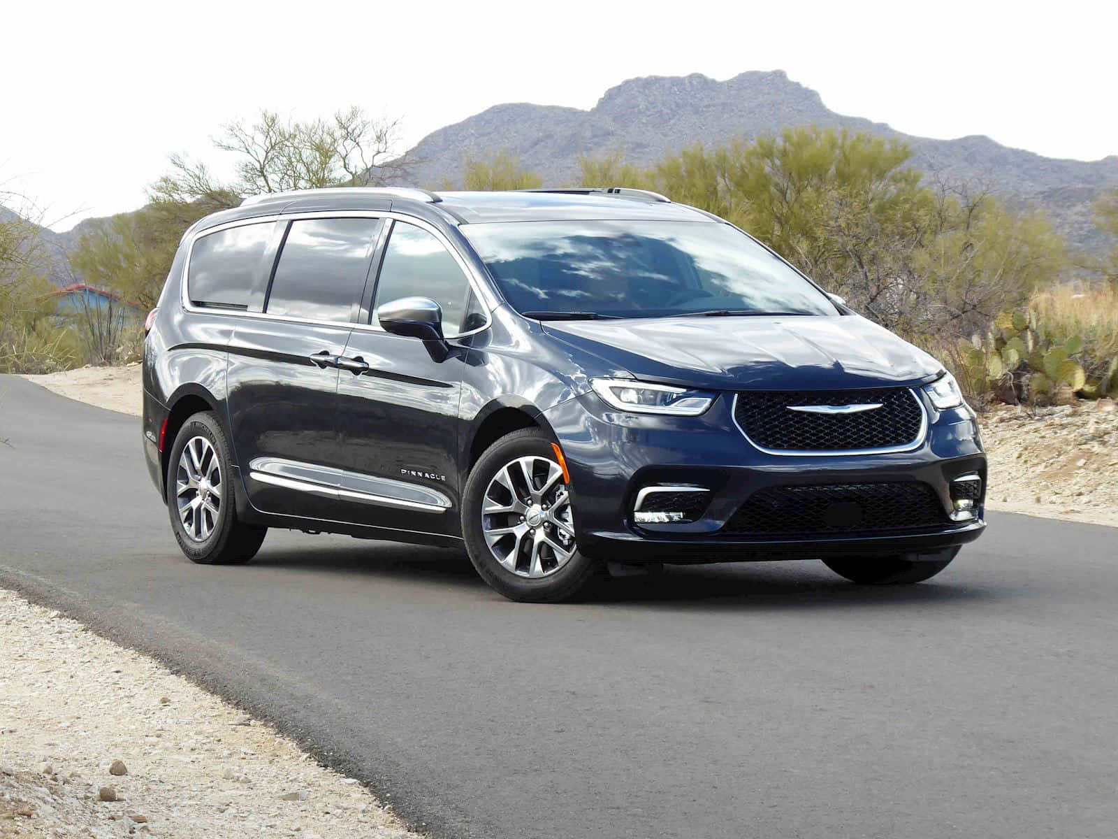 Chrysler Pacifica 桌布 壁紙 — 一架時尚的深藍色 Chrysler Pacifica 小型貨車在沙漠公路上行駛，背景有山脈和仙人掌。