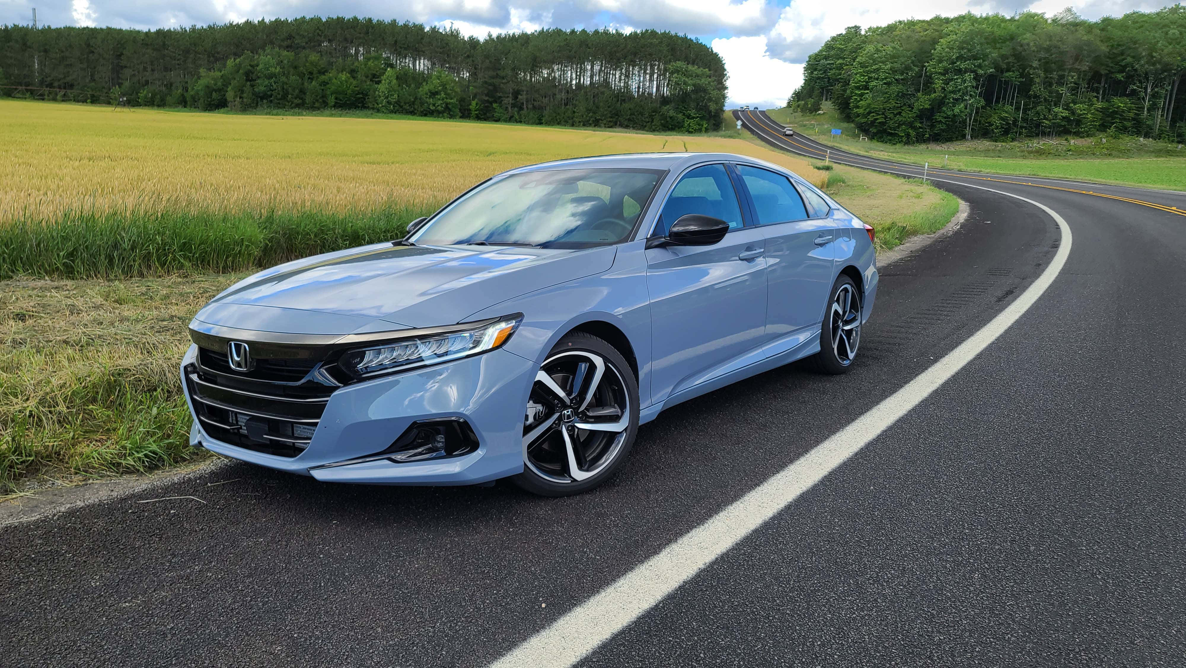 Honda Accord 桌布 壁紙 — 一架時尚的淺藍色本田房車停泊在蜿蜒的鄉村道路上，旁邊是金黃色的田野，天空部分多雲。