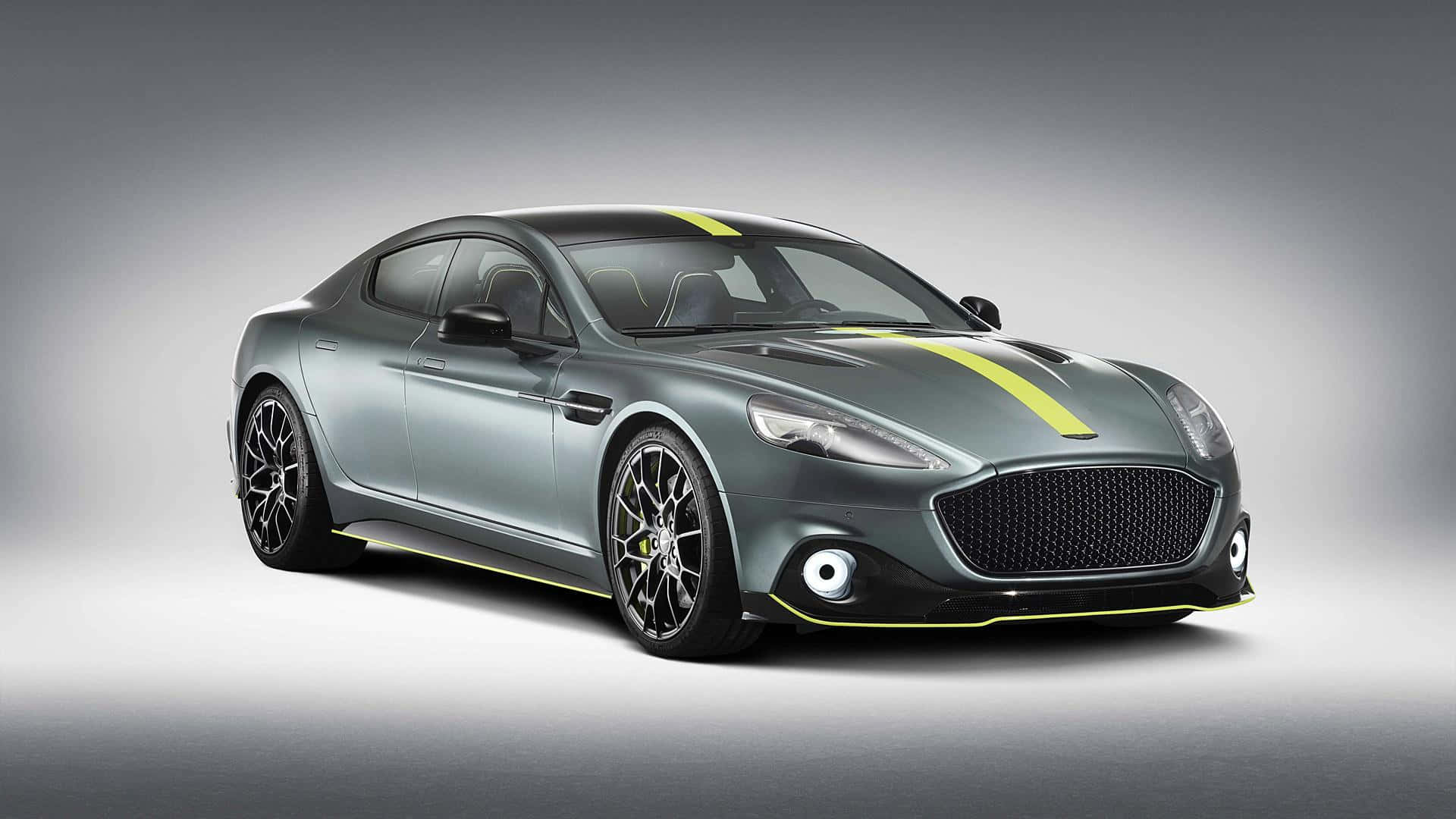 Aston Martin Rapide S 桌布 壁紙 — 一架時尚的灰色 Aston Martin，帶有醒目的黃色賽車條紋和黑色車輪，在漸變灰色工作室背景前展示。
