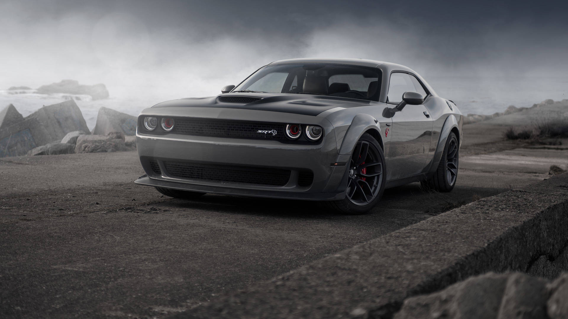 灰色 Dodge Challenger SRT Hellcat 在風暴中的海岸公路上，海浪拍打和混凝土屏障。 — Dodge challenger GIF 壁紙