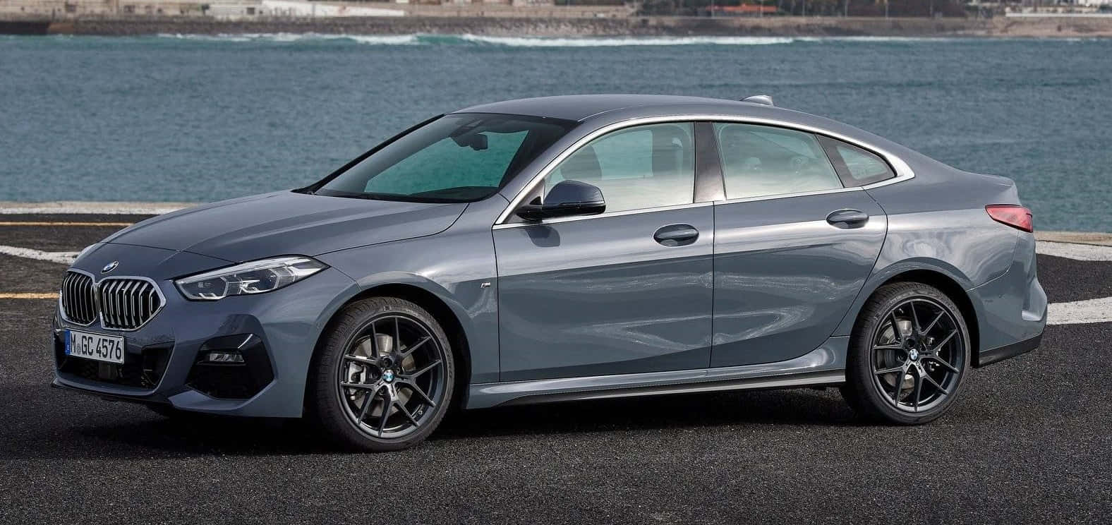 Bmw 2 Series 桌布 壁紙 — 一架時尚的灰色寶馬房車停泊在沿海公路上，背後有海浪拍打。