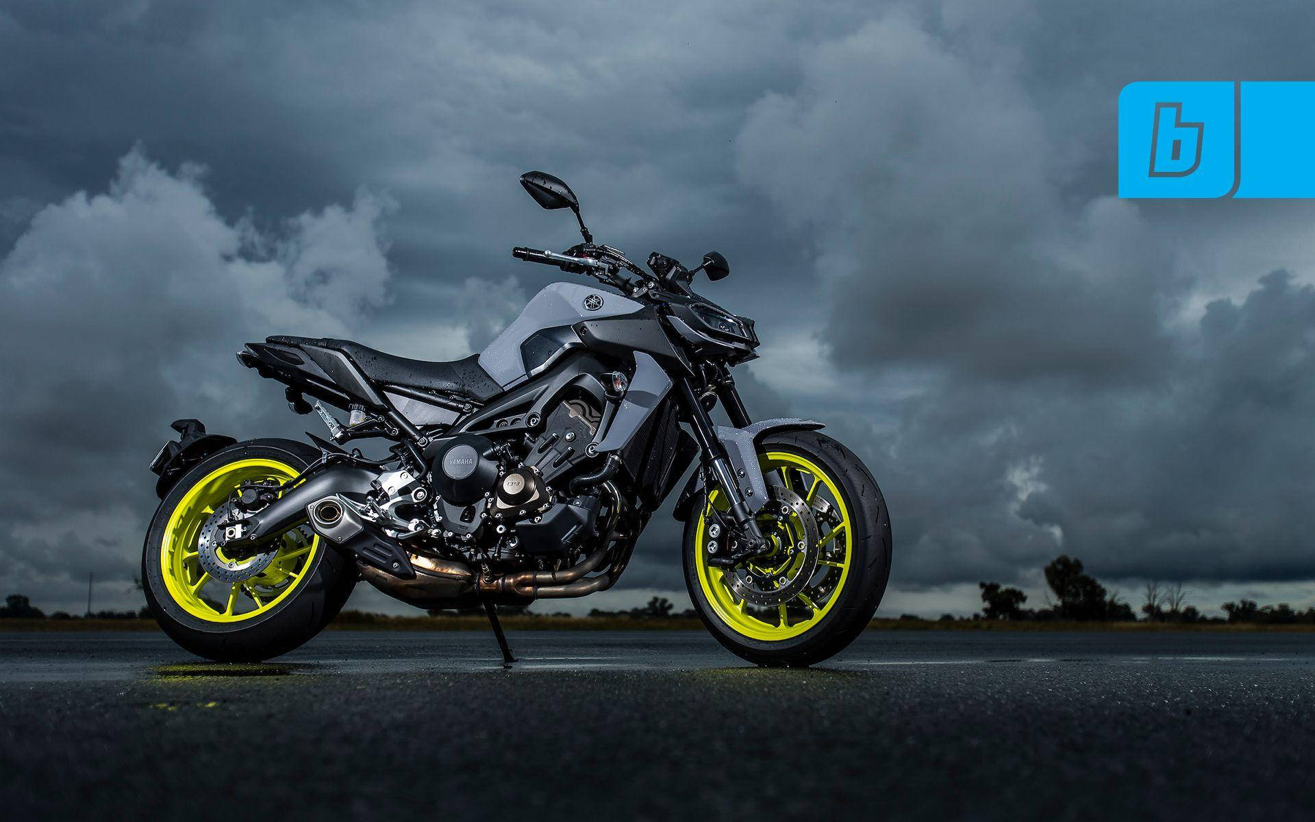 yamaha mt 15 桌布 壁紙 — 一架時尚的灰色電單車配備螢光黃色車輪，在戲劇性的暴風雨天空下，佇立在潮濕的瀝青路面上。
