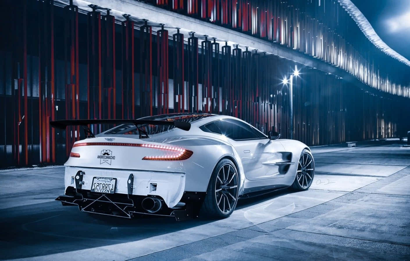 Aston Martin One-77 桌布 壁紙 — 一架時尚的白色 Aston Martin Vantage 跑車，帶有發光的尾燈，停在現代城市隧道中，在戲劇性的藍色和紅色燈光下。