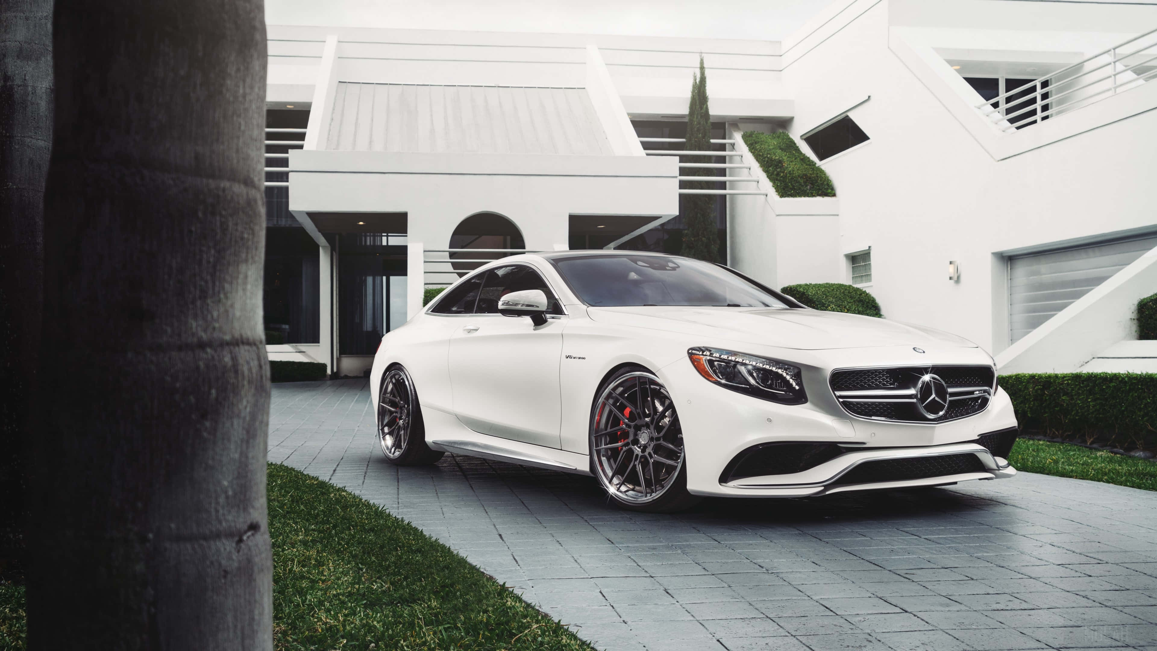 4K Mercedes 桌布 壁紙 — 一架時尚的白色 Mercedes-AMG S63 Coupe 停泊在現代白色豪宅前的瓷磚車道上，周圍有棕櫚樹。