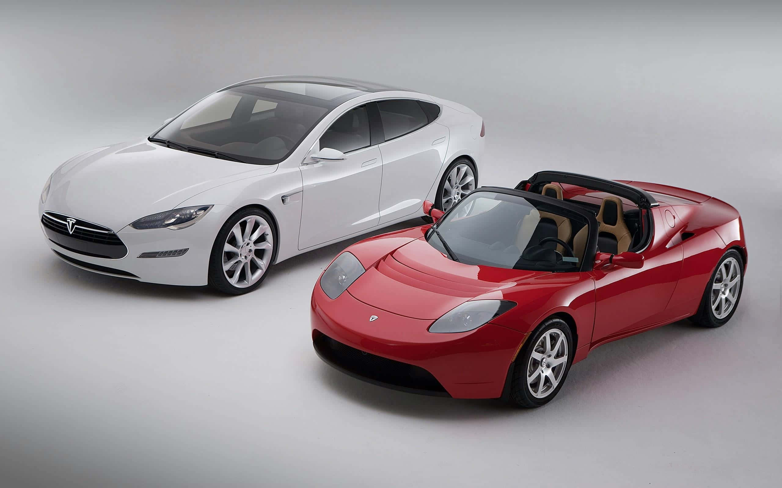 Car Model 桌布 壁紙 — 一架時尚的白色 Tesla Model S 房車和一輛充滿活力的紅色 Tesla Roadster 開篷車在簡約的攝影棚地板上並排展示。