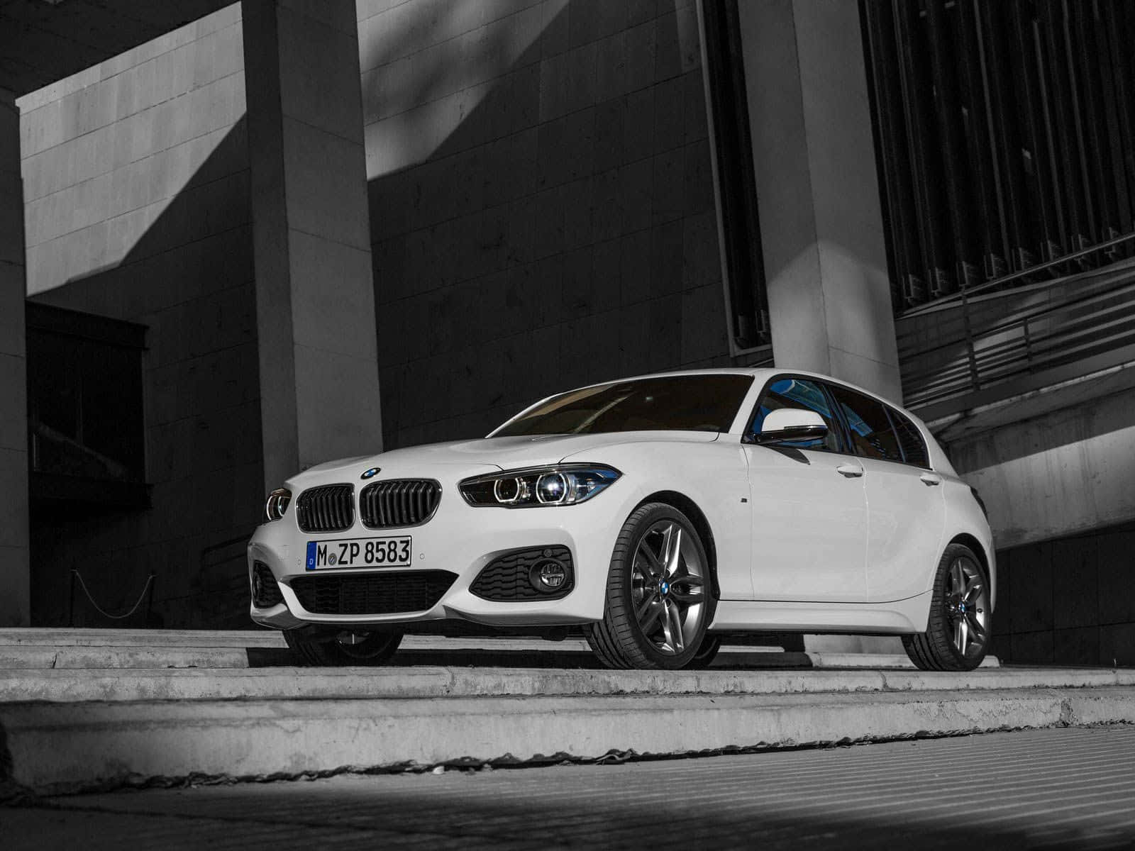Bmw 1 Series 桌布 壁紙 — 一架時尚的白色BMW 1系掀背車停在混凝土階梯上，背景為現代建築，光影對比強烈。