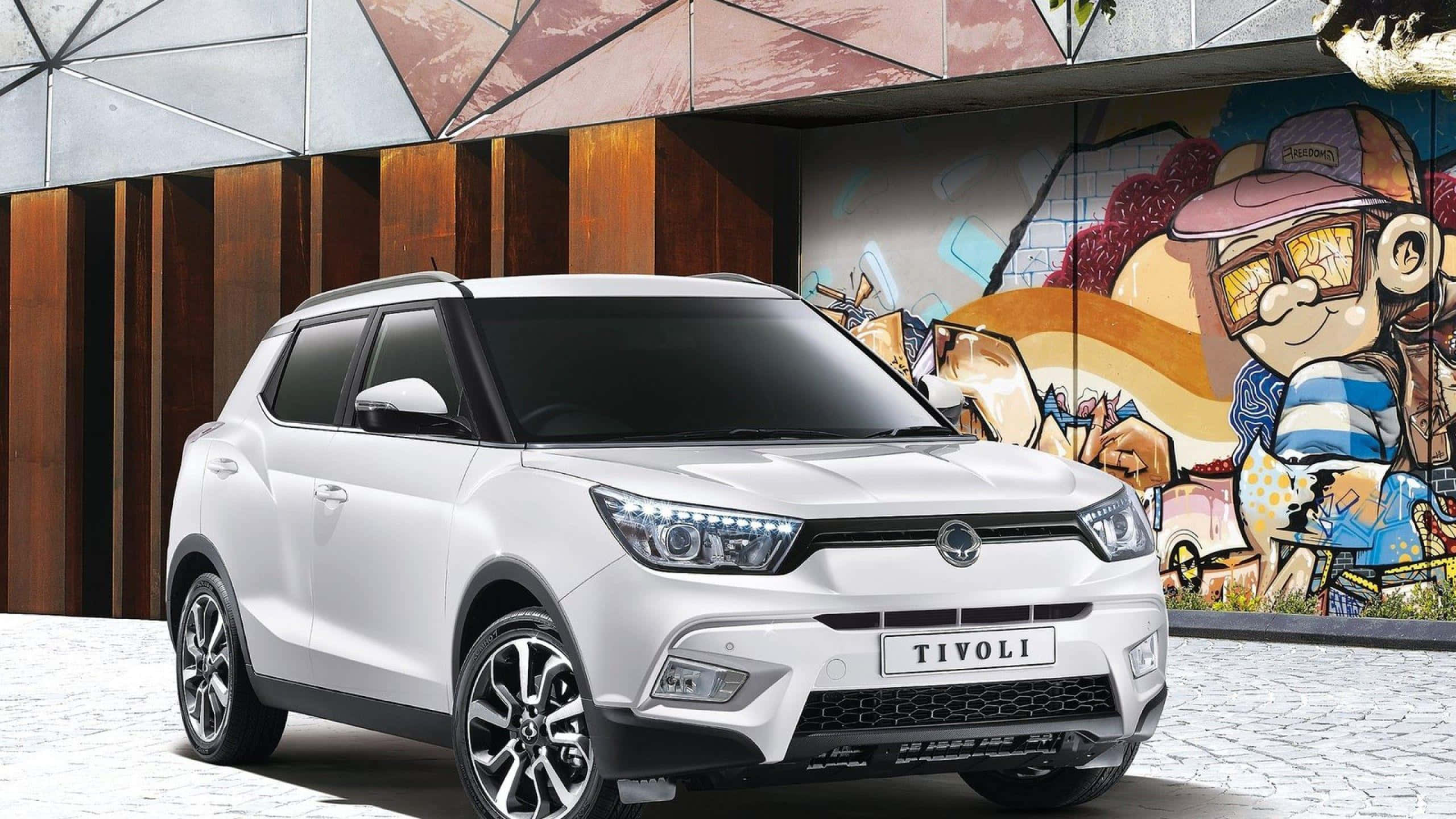 Ssangyong 桌布 壁紙 — 一架時尚的白色SsangYong Tivoli SUV停泊在充滿活力的塗鴉壁畫和現代木牆前。