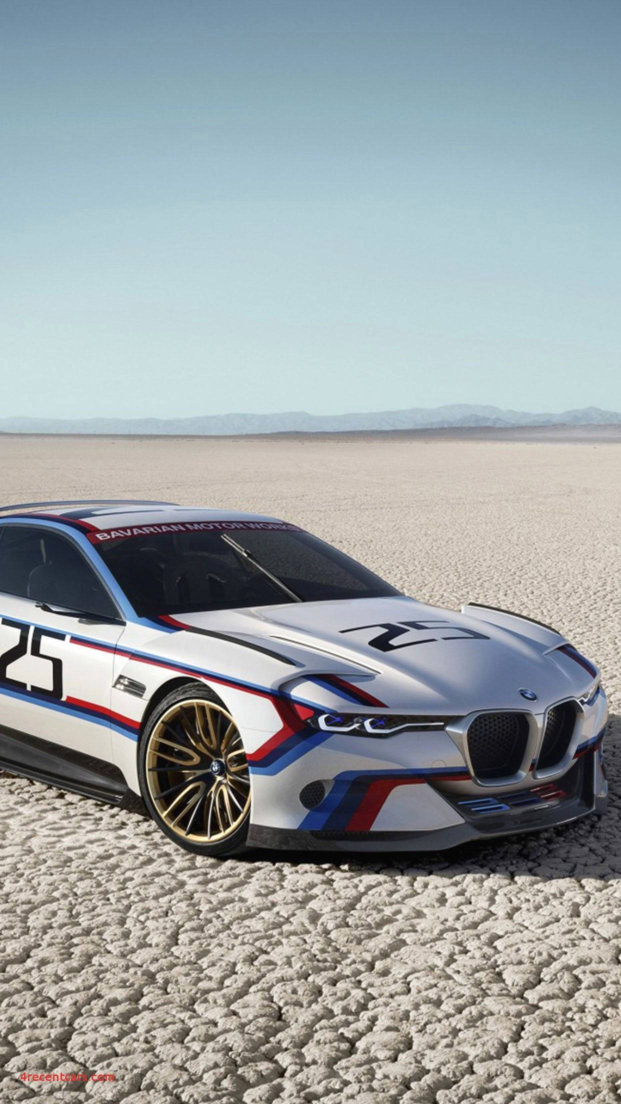 CLS Hommage BMW iPhone X 壁紙 — 一架時尚的白色寶馬賽車，帶有藍色、紅色和金色點綴，停在晴朗天空下龜裂的沙漠地面上。