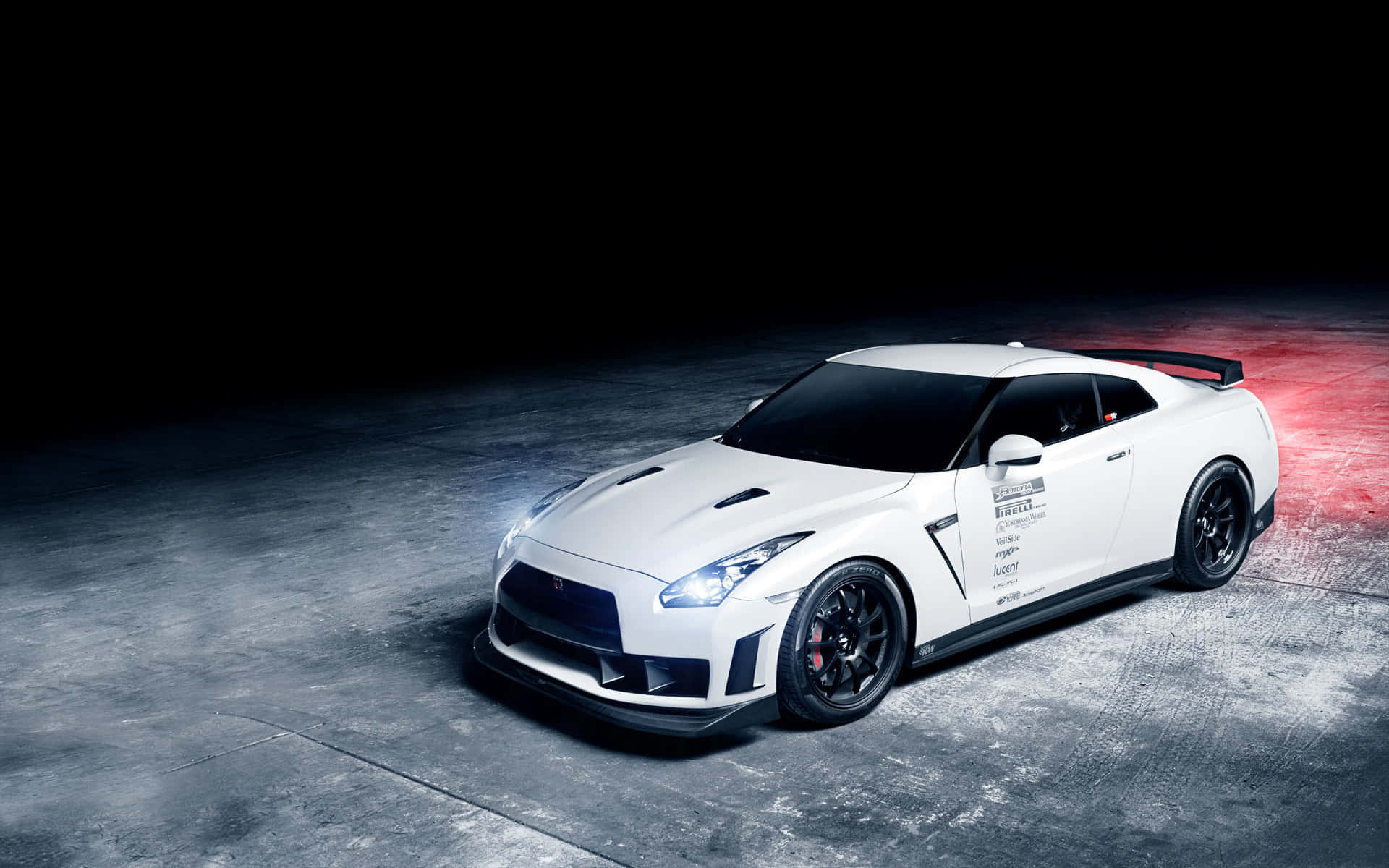 Gtr 桌布 壁紙 — 一架時尚的白色日產GT-R賽車在戲劇性的工作室燈光下，在帶有紅色重點照明的粗糙混凝土地板上發光。