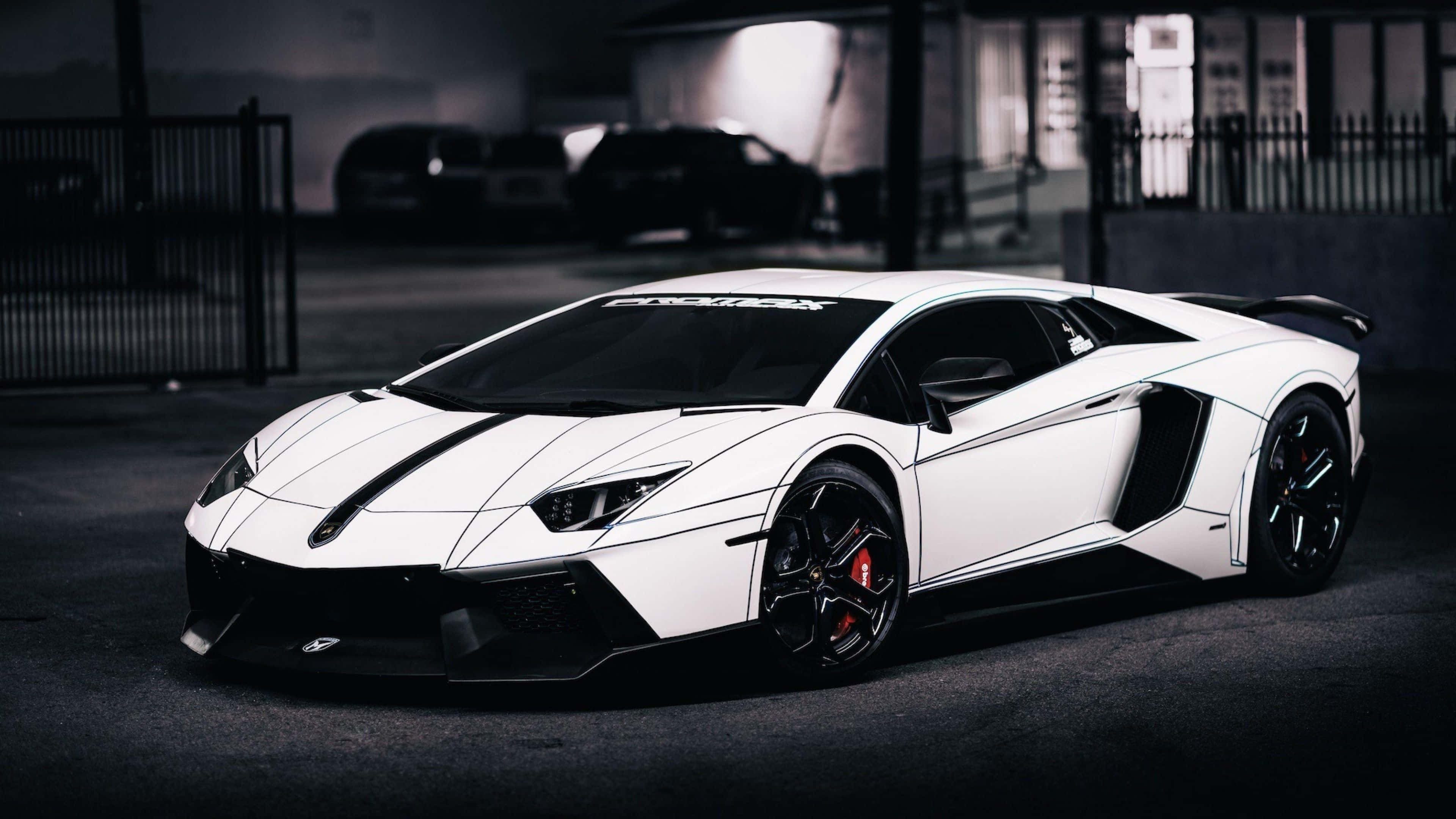 林寶堅尼 4K 桌布 壁紙 — 一架時尚的白色林寶堅尼Aventador，帶有黑色飾邊和紅色制動卡鉗，停泊在燈光昏暗的城市車庫中。