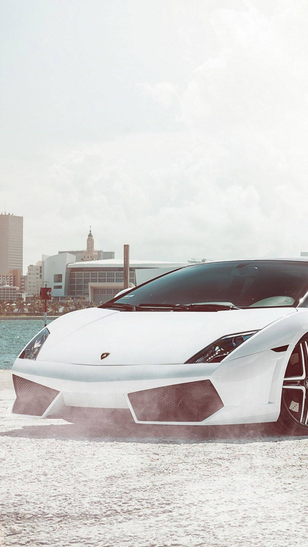 Cool Car 桌布 壁紙 — 一架時尚的白色林寶堅尼在淺水中飄移，背景是朦朧的現代城市天際線。