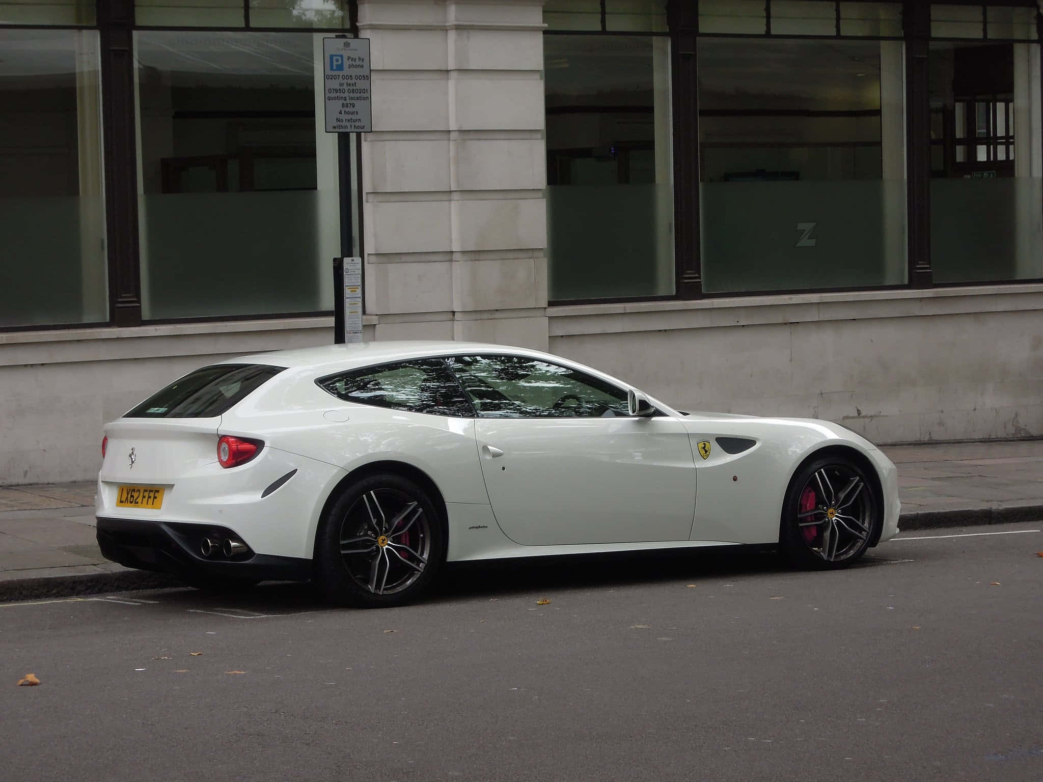 Ferrari Ff 桌布 壁紙 — 一架時尚的白色法拉利FF停泊在城市街道上，旁邊是一棟帶有大窗戶的現代建築。