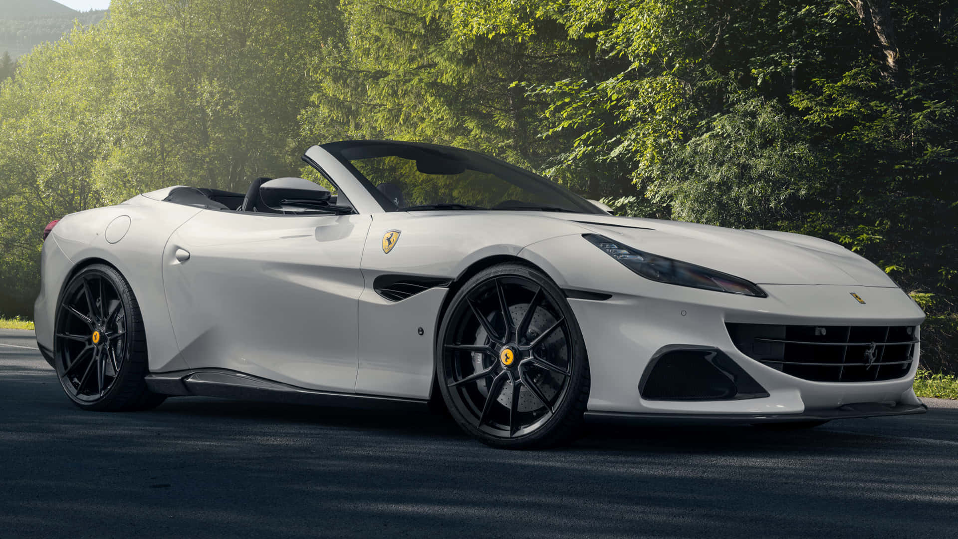 Ferrari Portofino 桌布 壁紙 — 一架時尚的白色法拉利敞篷車停泊在森林道路上，背景是茂密的綠樹。