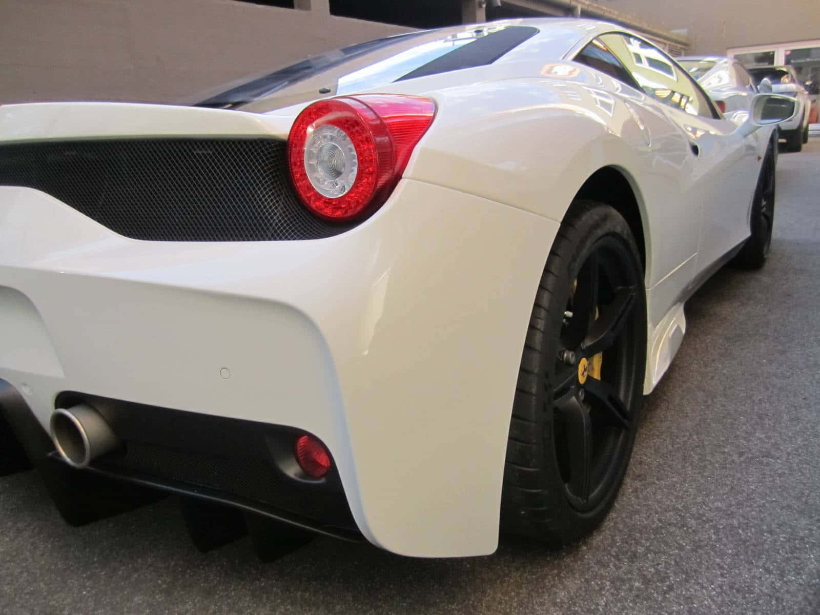 Ferrari 458 Speciale 桌布 壁紙 — 一架時尚的白色法拉利跑車，帶有黑色飾邊和紅色尾燈，停放在灰色地板的室內。